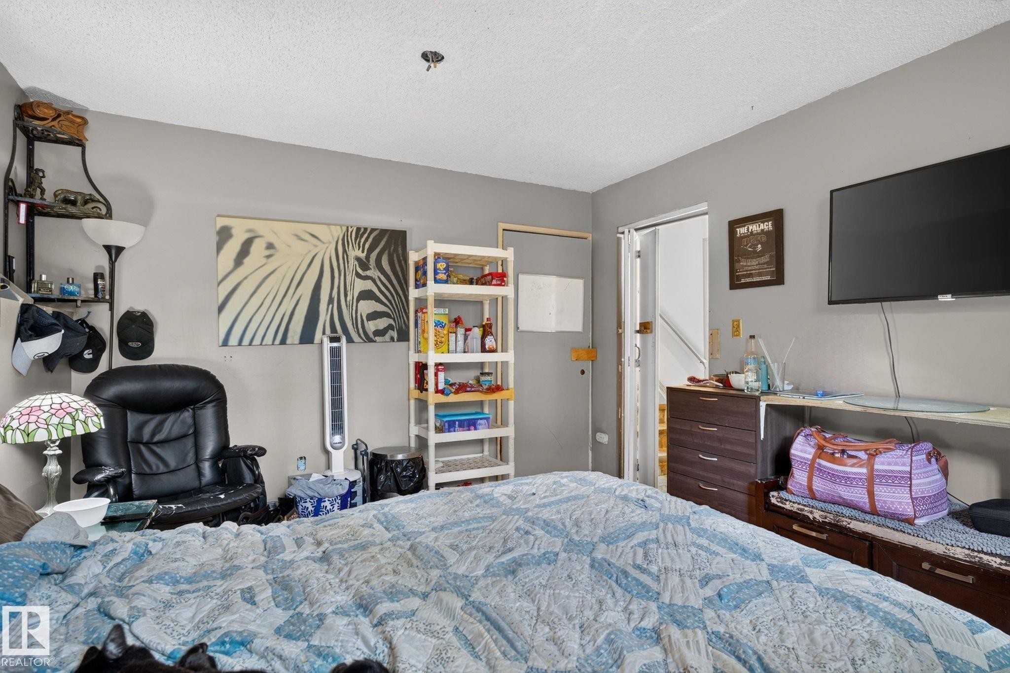 Spacious room featuring neutral gray walls, a built-in shelf unit, and a wall-mounted television - 8316 157 Avenue, Edmonton, AB