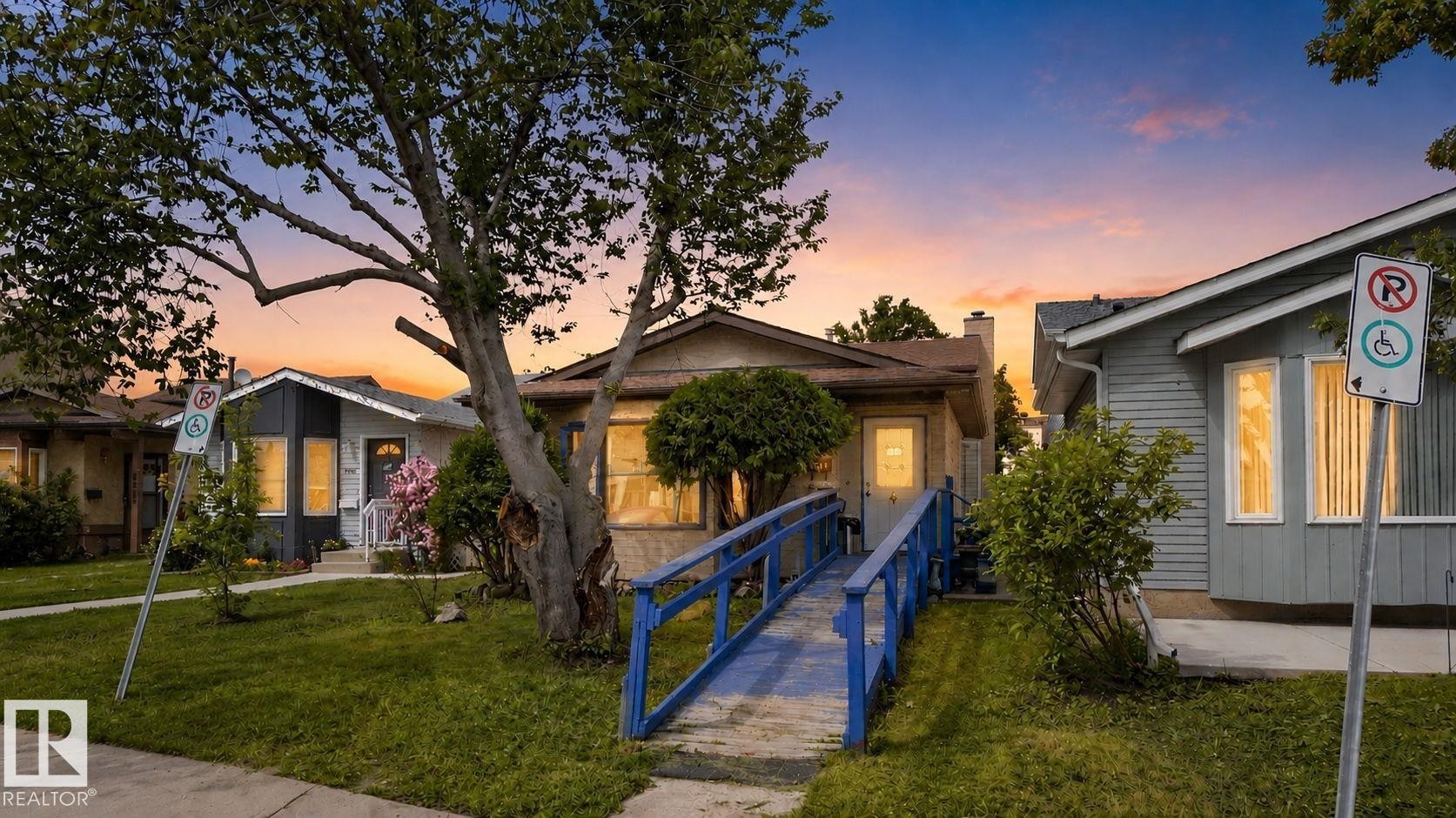 Front exterior with mature trees and a prominent blue accessibility ramp - 8316 157 Avenue, Edmonton, AB