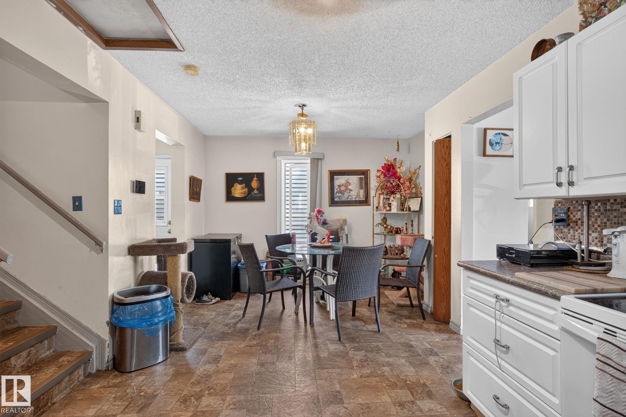 Open concept living area featuring wood-finish flooring, white cabinetry, and a mosaic tile backsplash - 8316 157 Avenue, Edmonton, AB