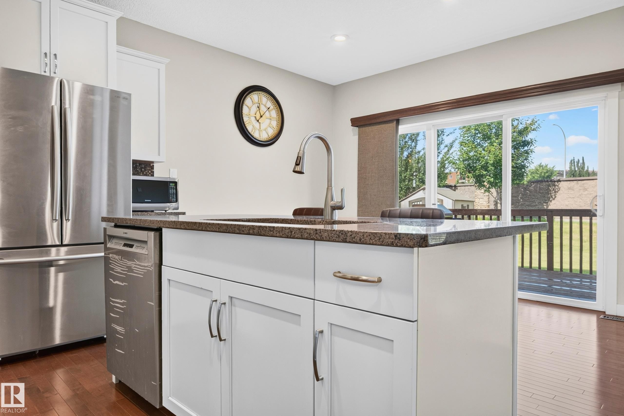Kitchen island featuring an undermount sink, gooseneck faucet, and stone countertop - 1512 Cunningham Cape, Edmonton, AB