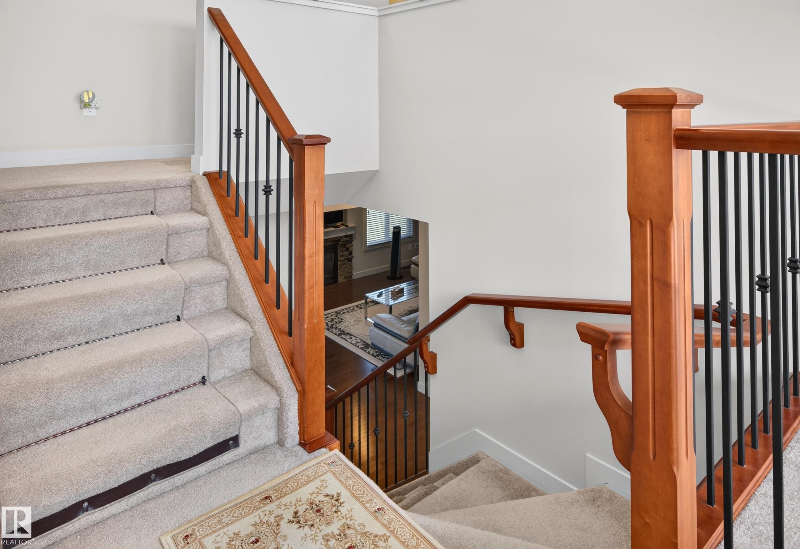 Carpeted staircase featuring wood-finish handrails and black metal balusters - 1512 Cunningham Cape, Edmonton, AB
