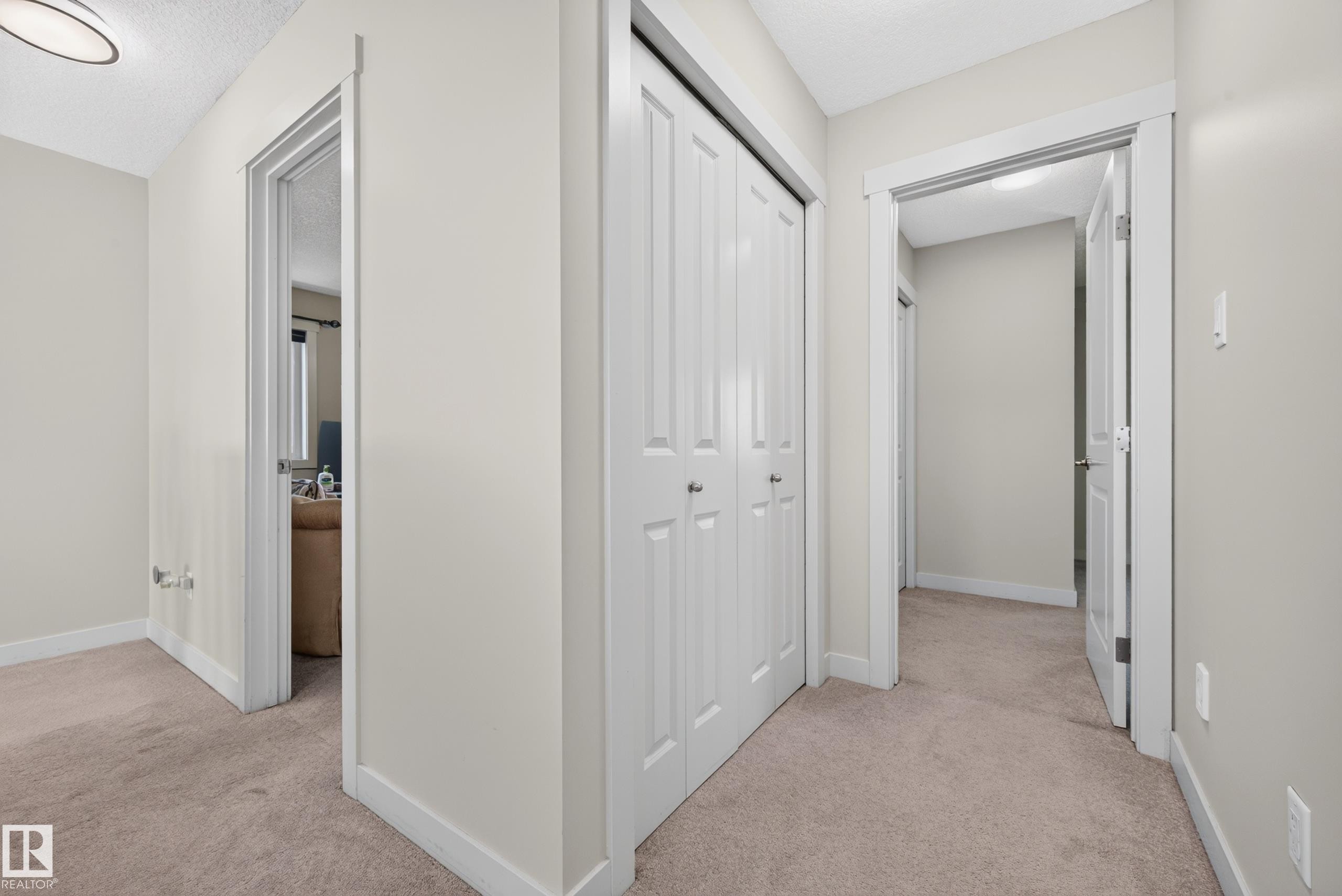 Hallway featuring light neutral wall paint, white trim, beige carpeting, a bi-fold closet, and recessed lighting - 1512 Cunningham Cape, Edmonton, AB