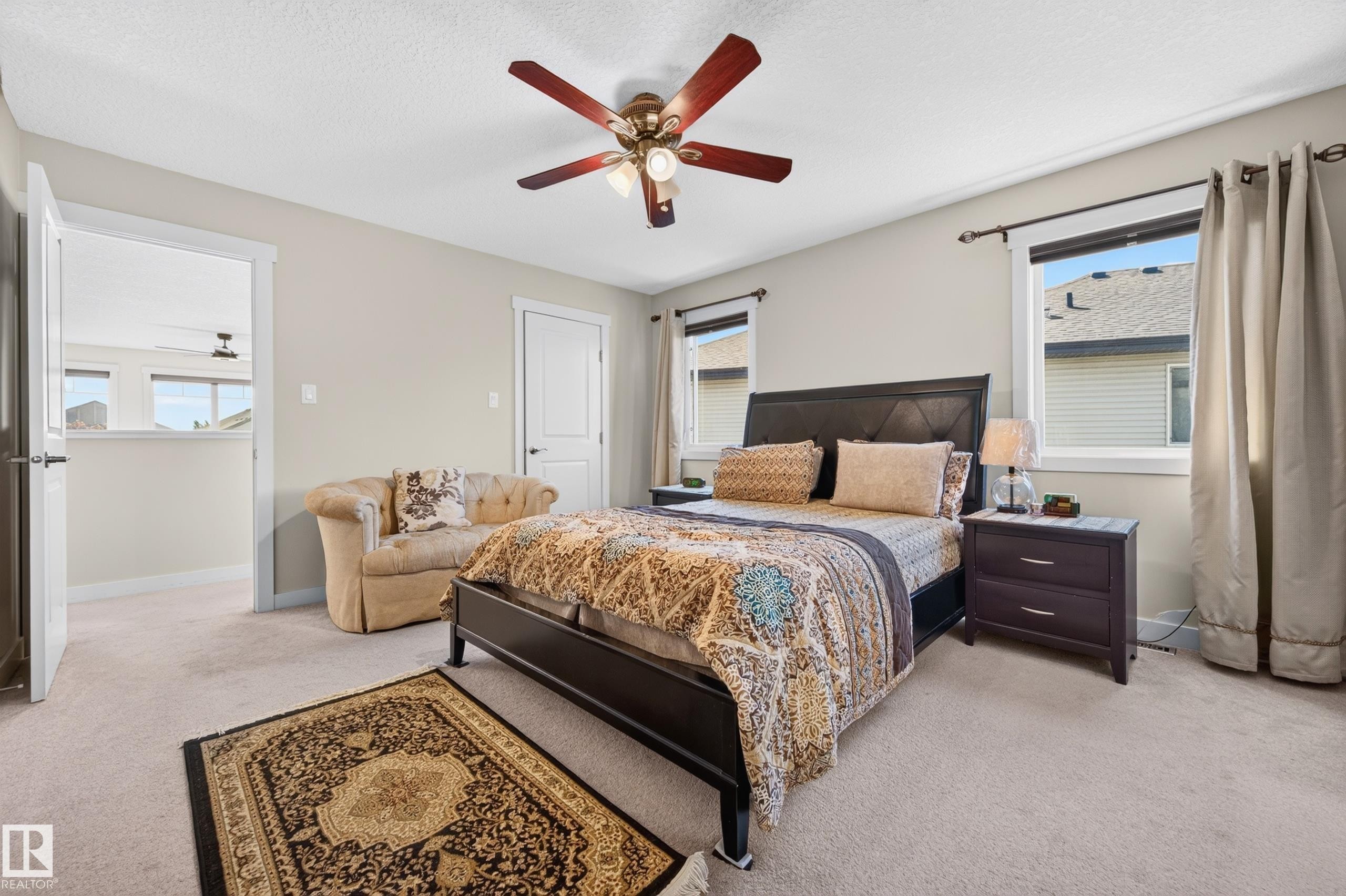 Carpeted room featuring a ceiling fan with light fixture, two windows with blinds and curtain rods, and a white interior door - 1512 Cunningham Cape, Edmonton, AB