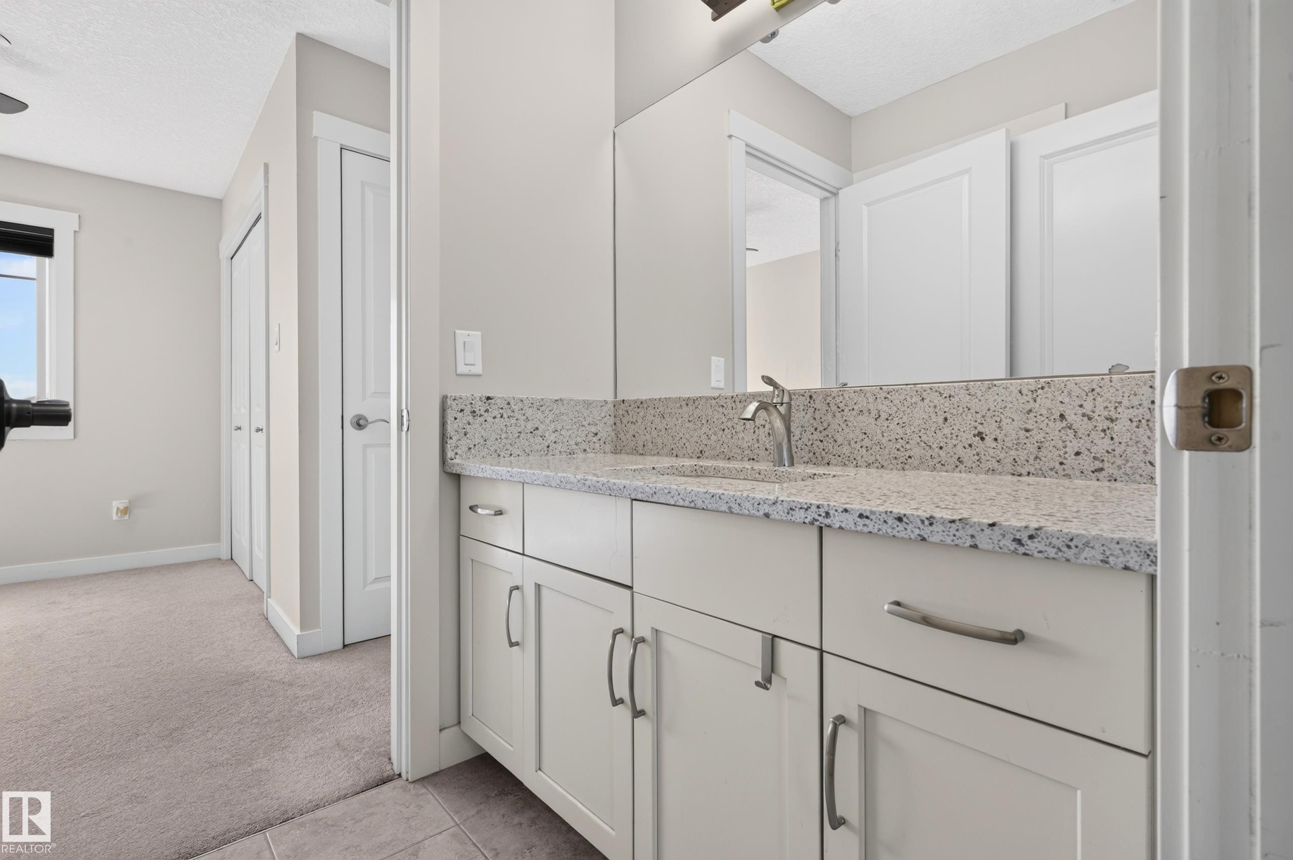 Bathroom vanity with a speckled countertop, undermount sink, and brushed nickel faucet - 1512 Cunningham Cape, Edmonton, AB