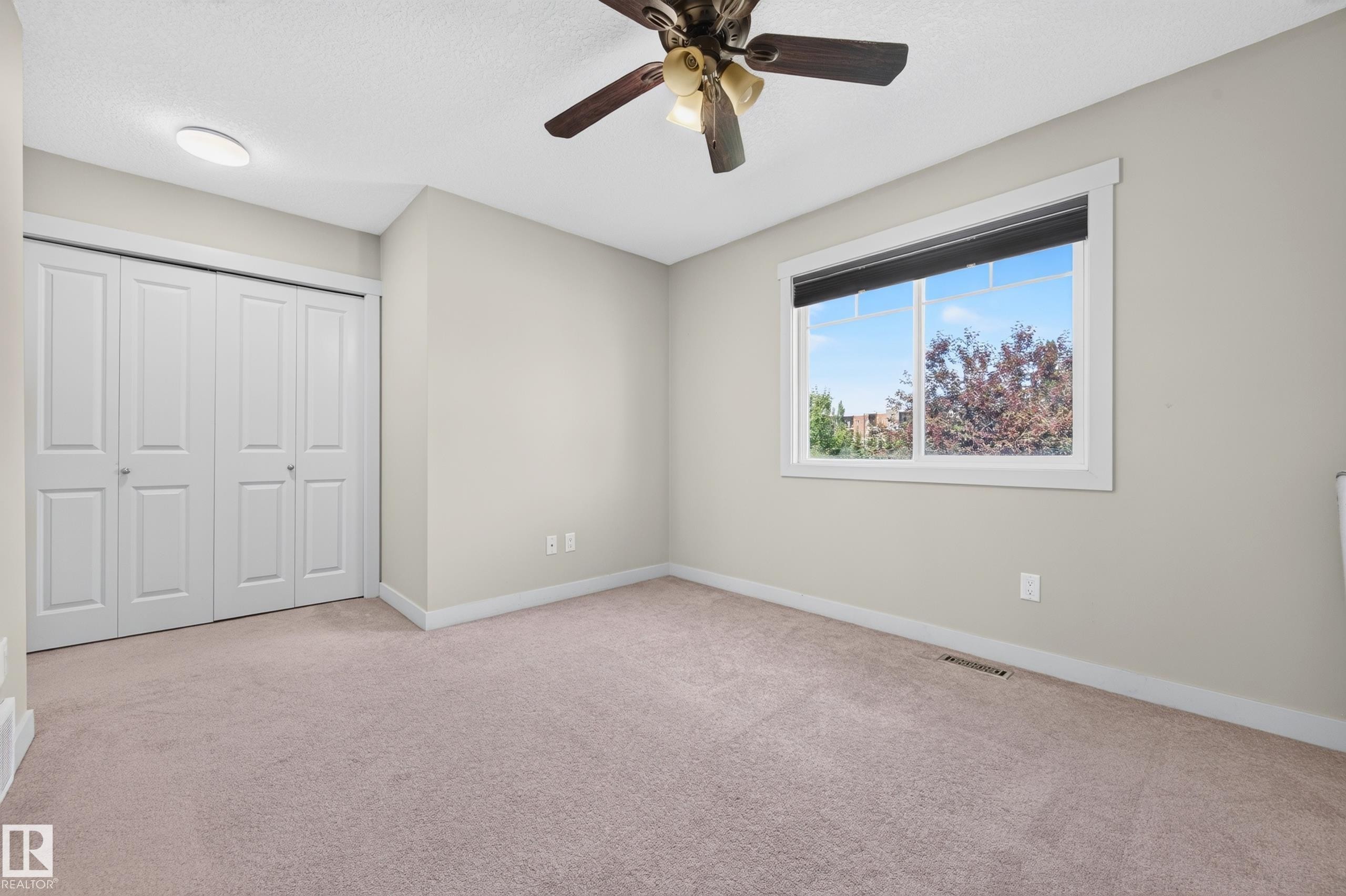 Neutral-toned wall paint and plush carpet flooring complement a white trim window - 1512 Cunningham Cape, Edmonton, AB