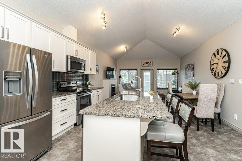 Open-concept kitchen and dining area featuring a vaulted ceiling and track lighting - 15 175 Mcconachie Drive, Edmonton, AB