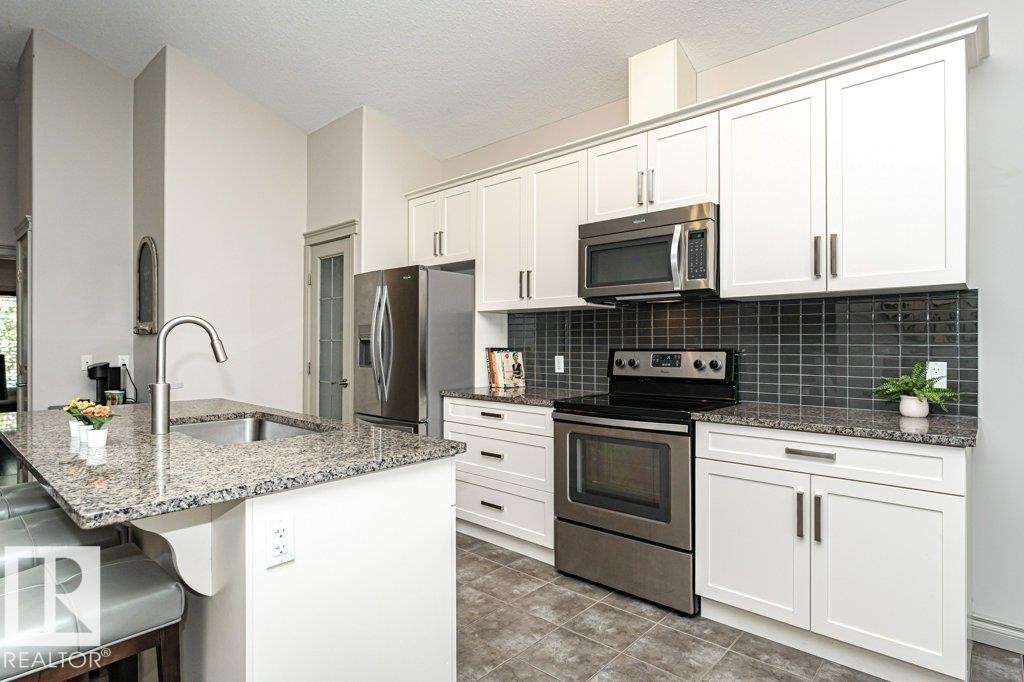 Modern kitchen featuring white cabinetry and stainless steel appliances - 15 175 Mcconachie Drive, Edmonton, AB