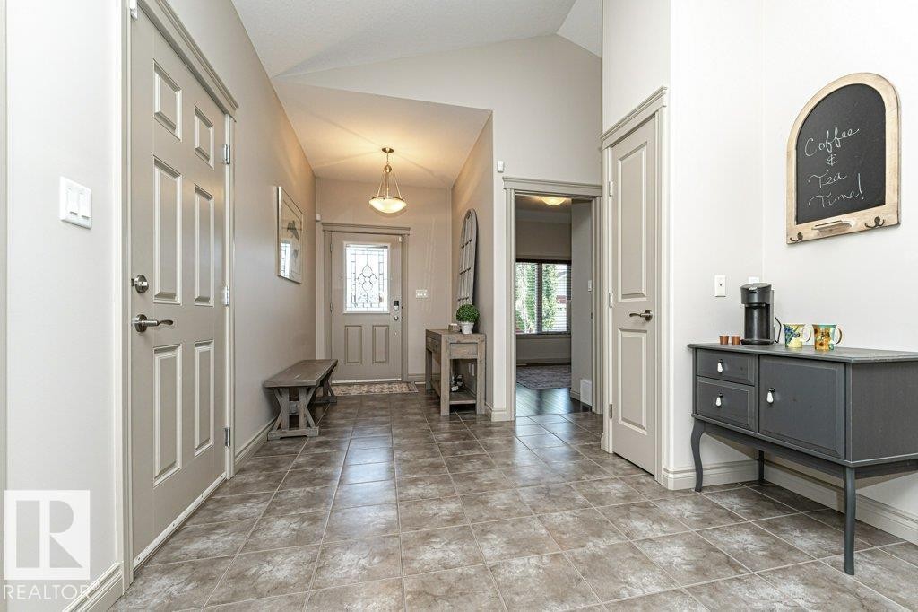 Spacious entryway featuring neutral-toned tile flooring, vaulted ceilings, and a light-colored front door with decorative glass inserts - 15 175 Mcconachie Drive, Edmonton, AB