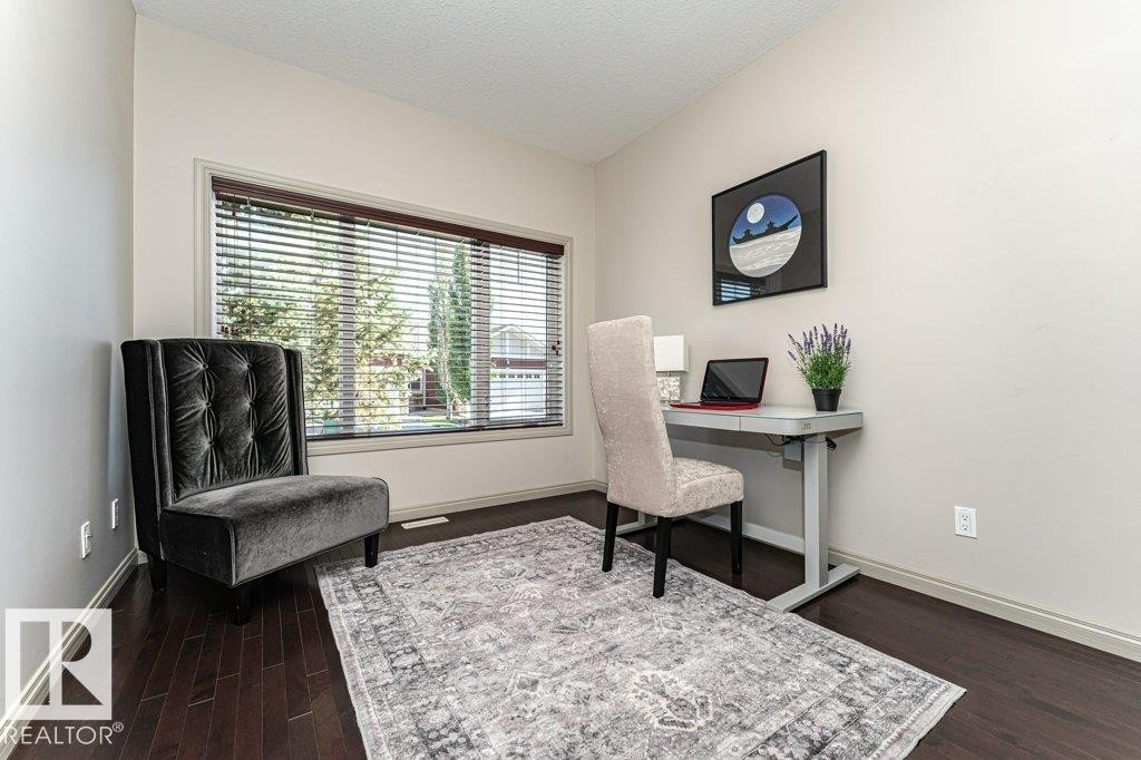 Bright room featuring dark wood-finish flooring, a large window with horizontal blinds, and neutral wall tones - 15 175 Mcconachie Drive, Edmonton, AB