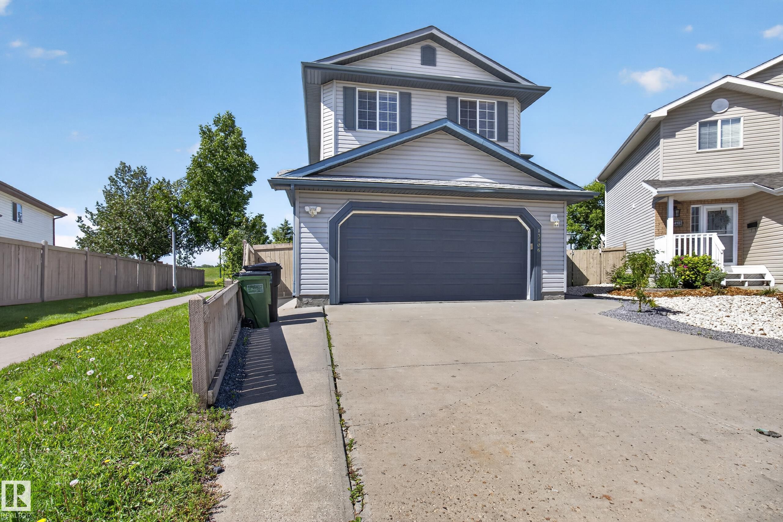 Two-story residence featuring light gray siding with dark gray trim accents and a matching garage door - 13406 32A Street, Edmonton, AB