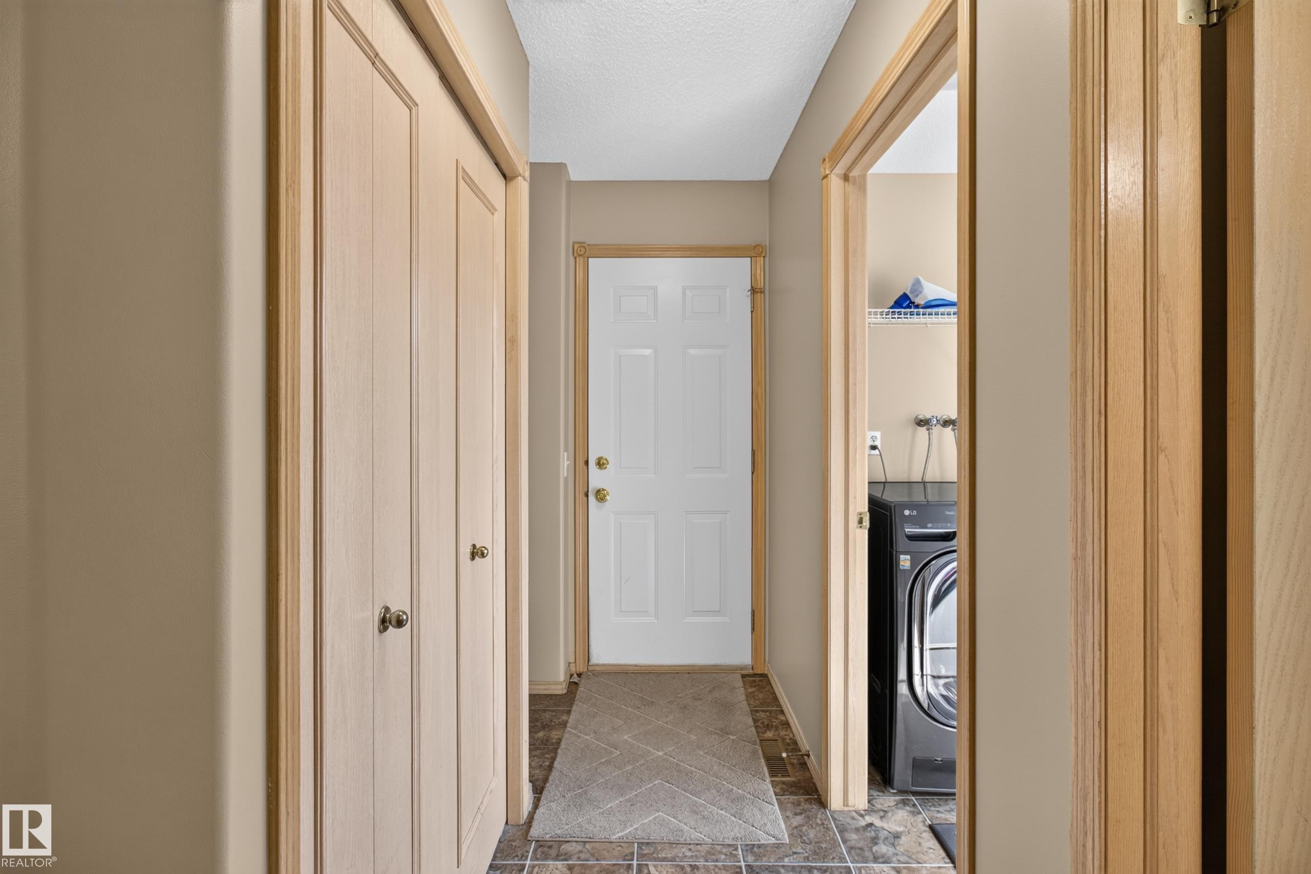 Hallway with light beige walls and wood-finish trim and doors - 13406 32A Street, Edmonton, AB