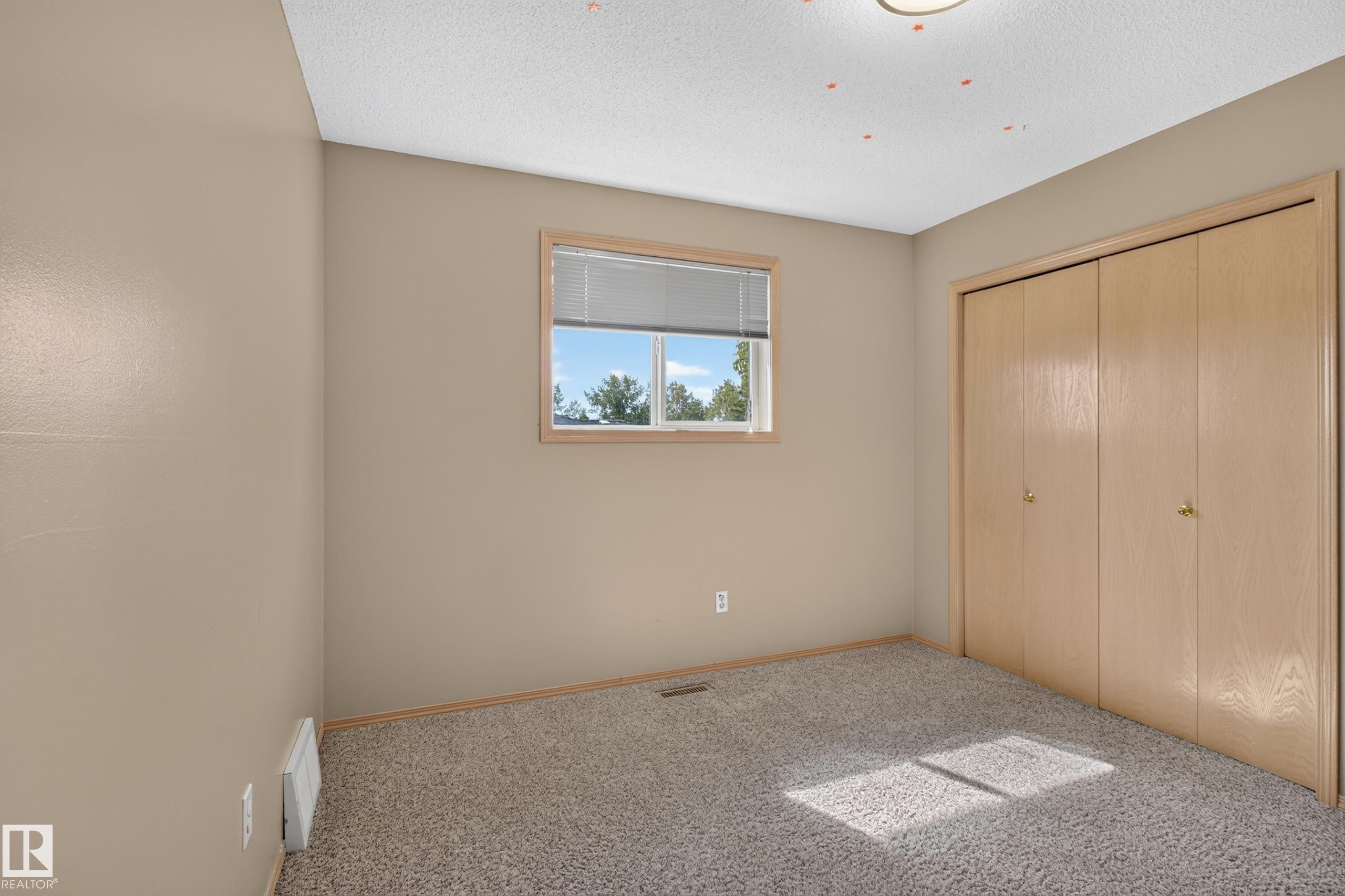 Room featuring neutral walls, textured carpeting, and a window with blinds - 13406 32A Street, Edmonton, AB