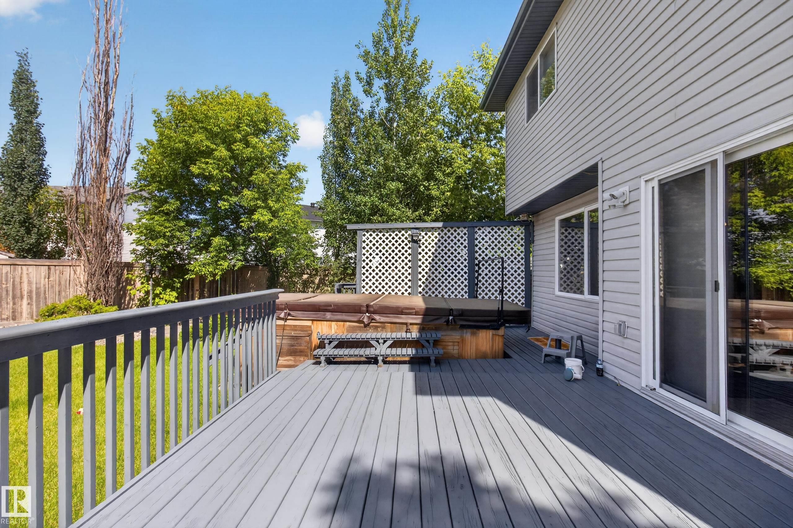 Expansive gray composite deck featuring a privacy screen and integrated spa - 13406 32A Street, Edmonton, AB