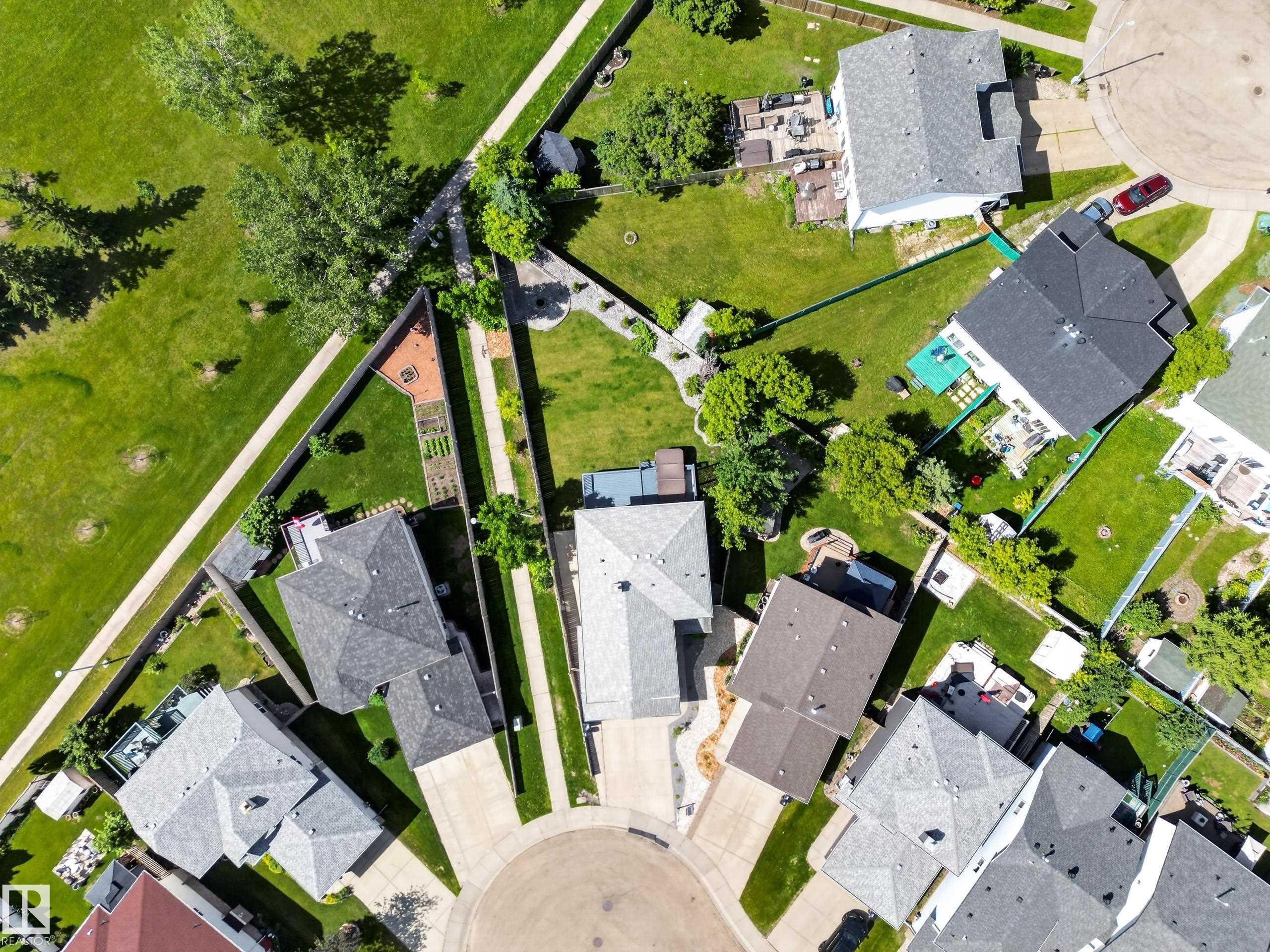 Aerial perspective of a residential neighborhood featuring several properties with pitched roofs, individual driveways, and green lawns - 13406 32A Street, Edmonton, AB