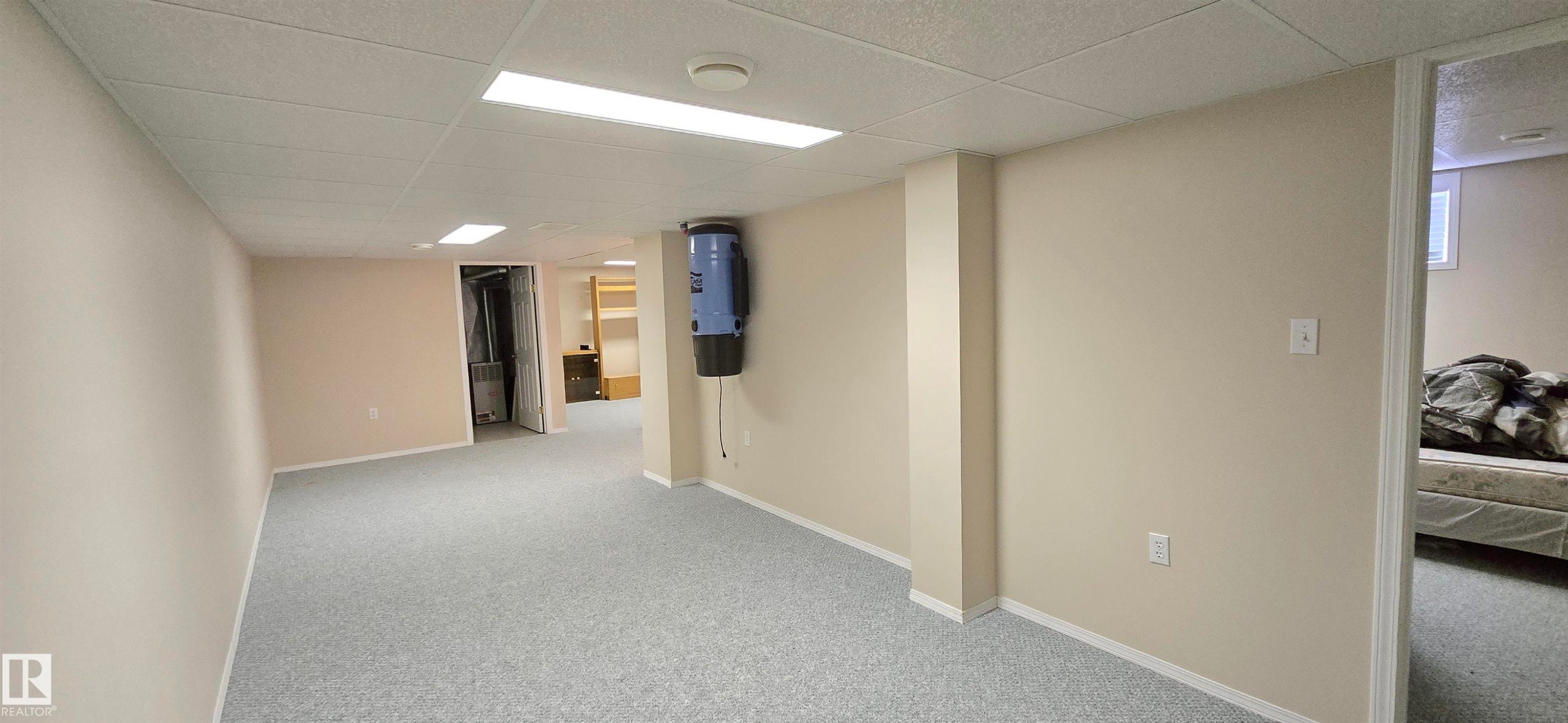 Spacious room with light-colored carpeting, neutral painted walls, and white trim - 4734 54A Avenue, Vegreville, AB - Indoor Photo Showing Other Room