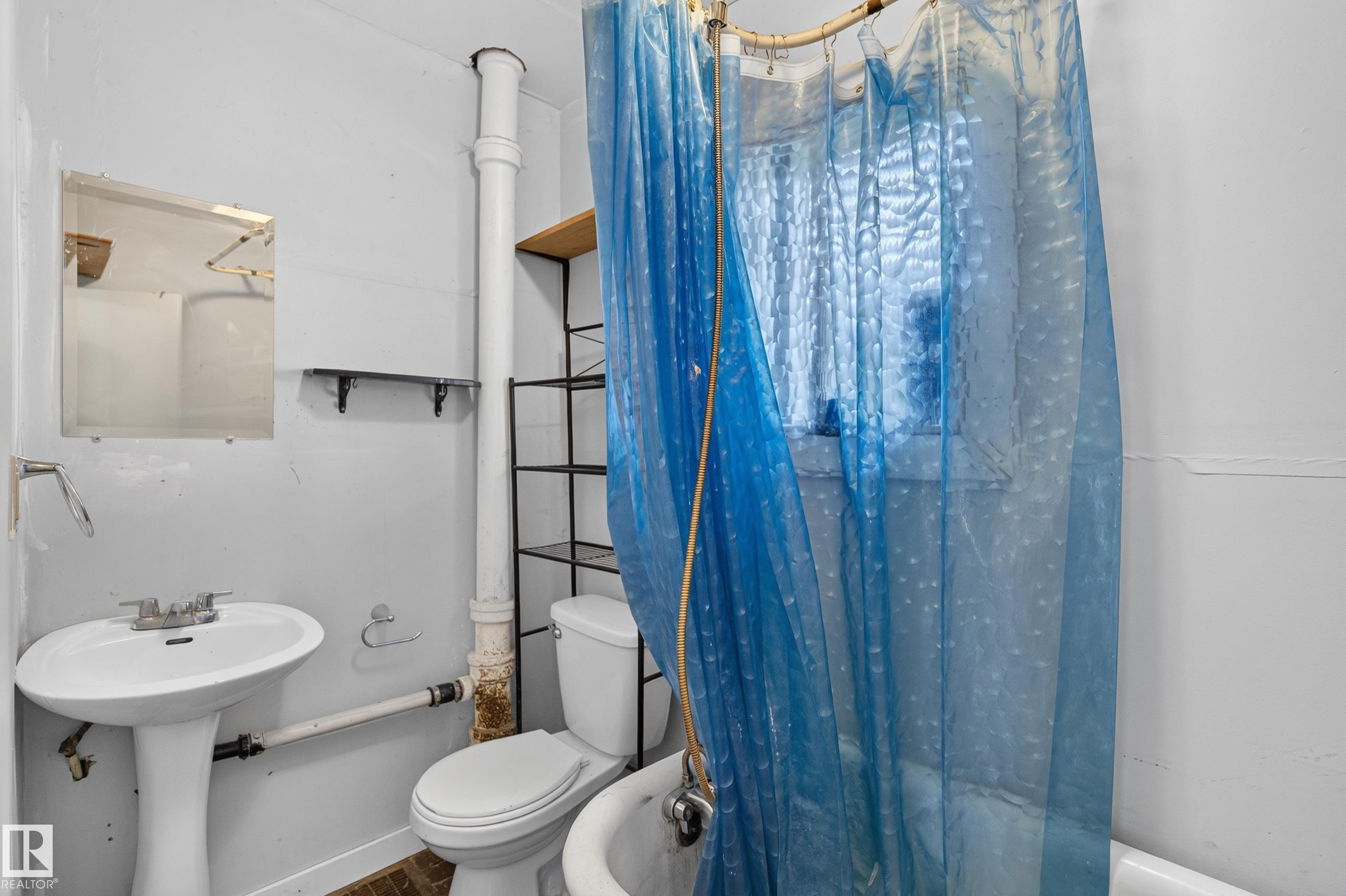 Bathroom featuring a pedestal sink, toilet, and a window - 11708 79 Street, Edmonton, AB
