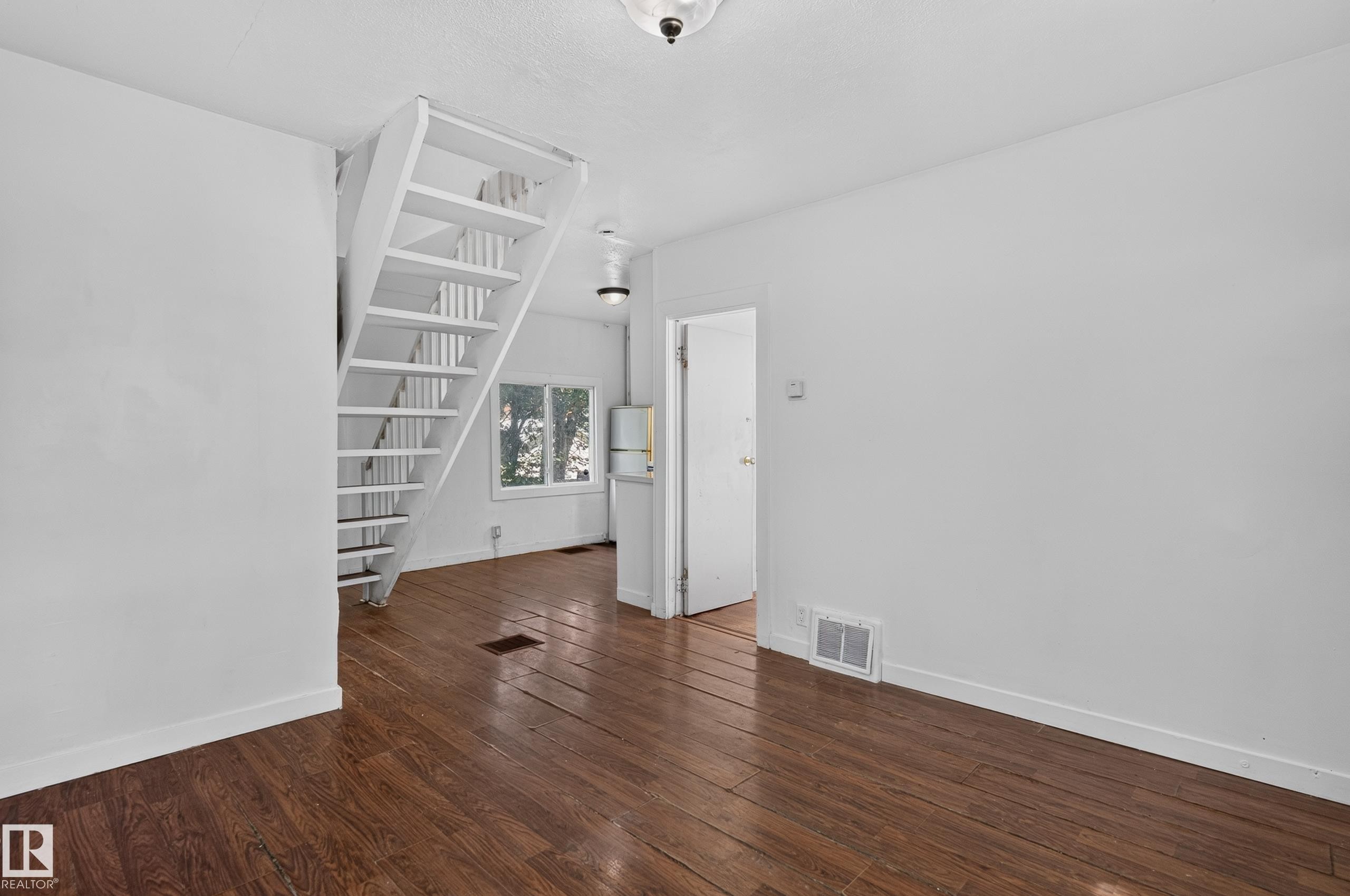 White-painted staircase with open risers and wood-finish flooring - 11708 79 Street, Edmonton, AB