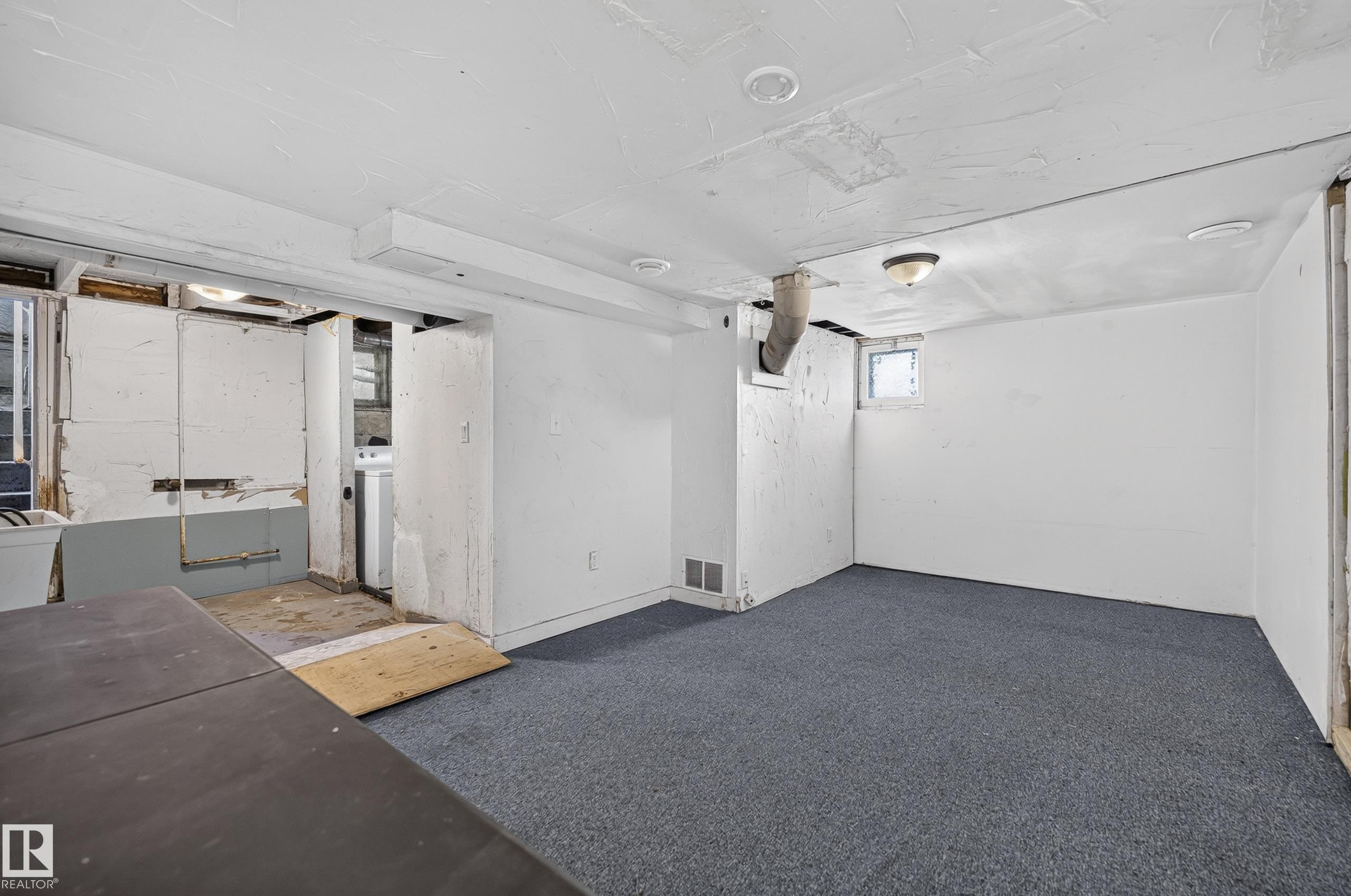Finished lower-level room featuring blue carpeting, white painted walls, and a small window - 11708 79 Street, Edmonton, AB