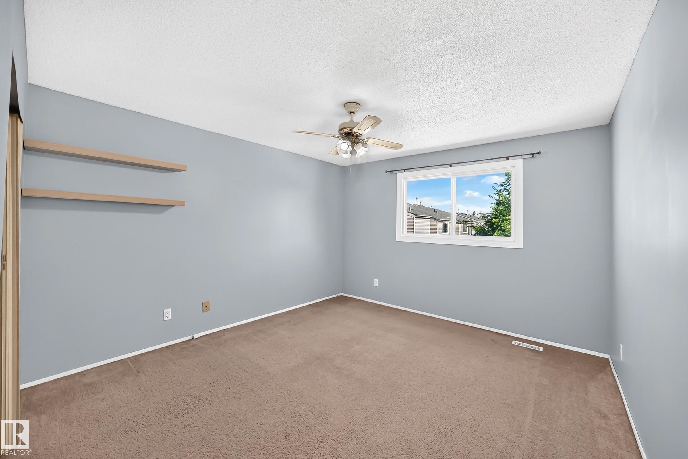 Spacious room featuring broadloom carpeting, light blue walls, and a textured white ceiling - 355 Northgate Terrace, Edmonton, AB