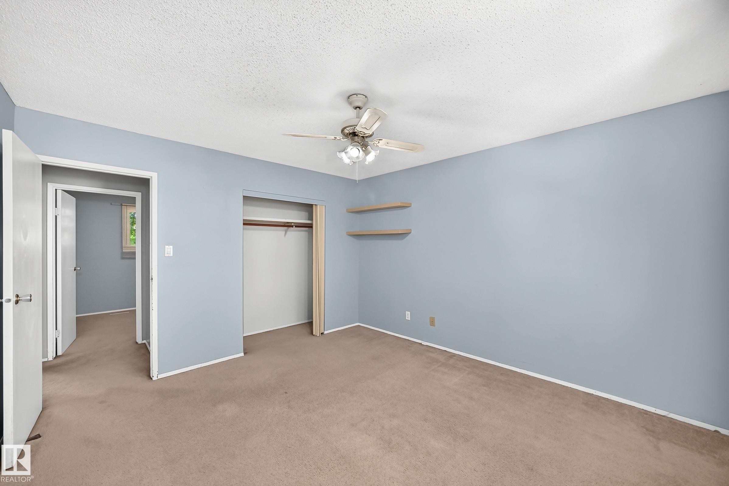 Bedroom featuring light blue walls, brown carpet, a ceiling fan, an open closet with a hanging rod, and two wall-mounted shelves - 355 Northgate Terrace, Edmonton, AB