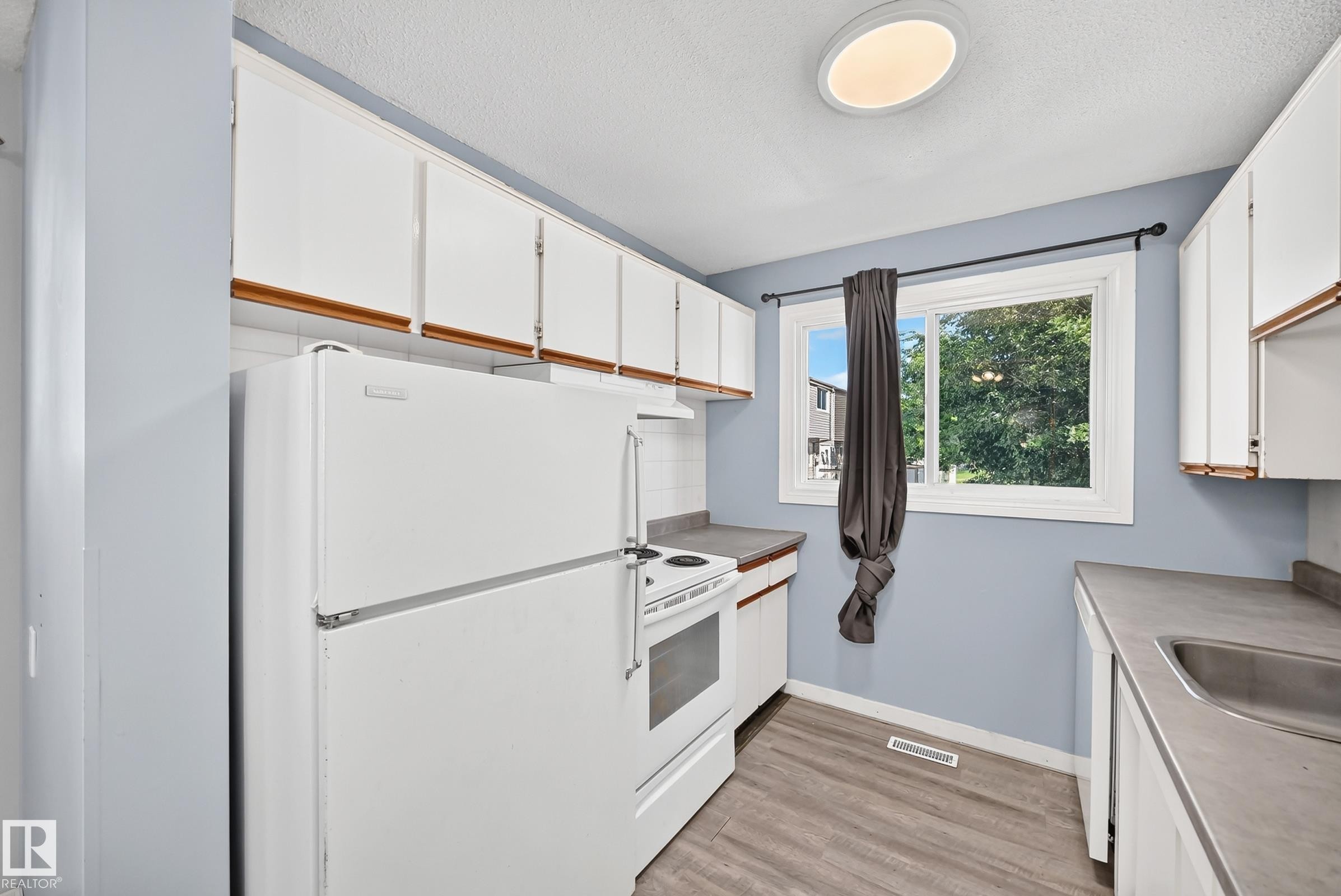 Kitchen featuring white cabinetry with wood-finish trim, laminate countertops, and wood-finish flooring - 355 Northgate Terrace, Edmonton, AB