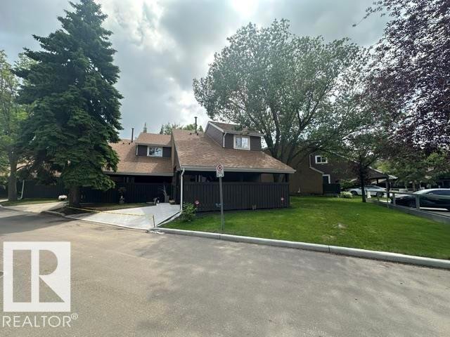 Townhome exterior featuring a brown facade, dormer windows, and a shingle roof - 18020 96 Avenue, Edmonton, AB