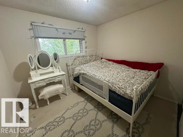 Carpeted room featuring a window with blinds, light-colored walls, and a ceiling light fixture - 18020 96 Avenue, Edmonton, AB