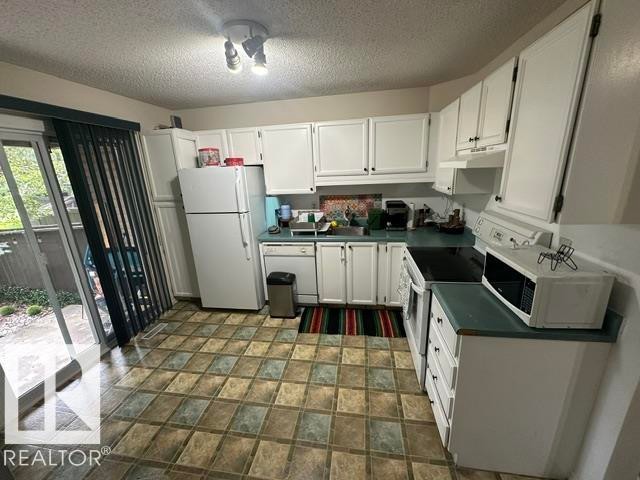 Kitchen featuring white cabinetry, a full suite of white appliances, and a tiled floor - 18020 96 Avenue, Edmonton, AB