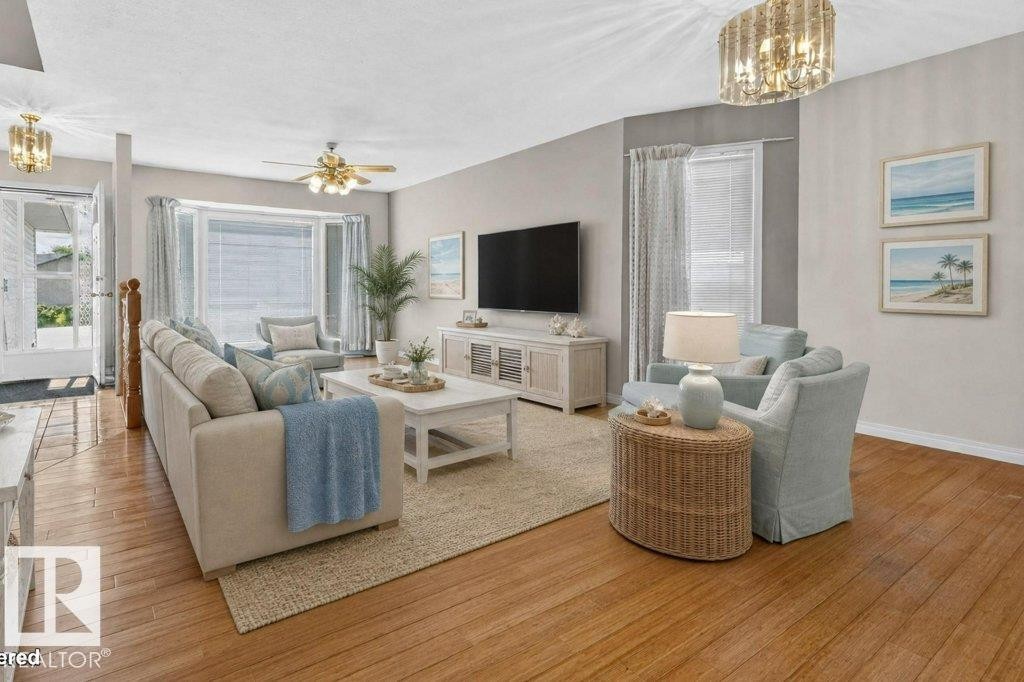Open living area featuring wood-finish flooring, a ceiling fan, and a bay window - 16524 99 Street Nw, Edmonton, AB - Indoor Photo Showing Living Room