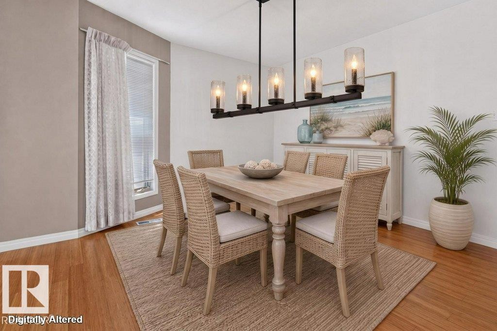 Dining area featuring a linear chandelier with five glass shades, wood-finish flooring, a window with blinds, and white baseboards - 16524 99 Street Nw, Edmonton, AB - Indoor Photo Showing Dining Room