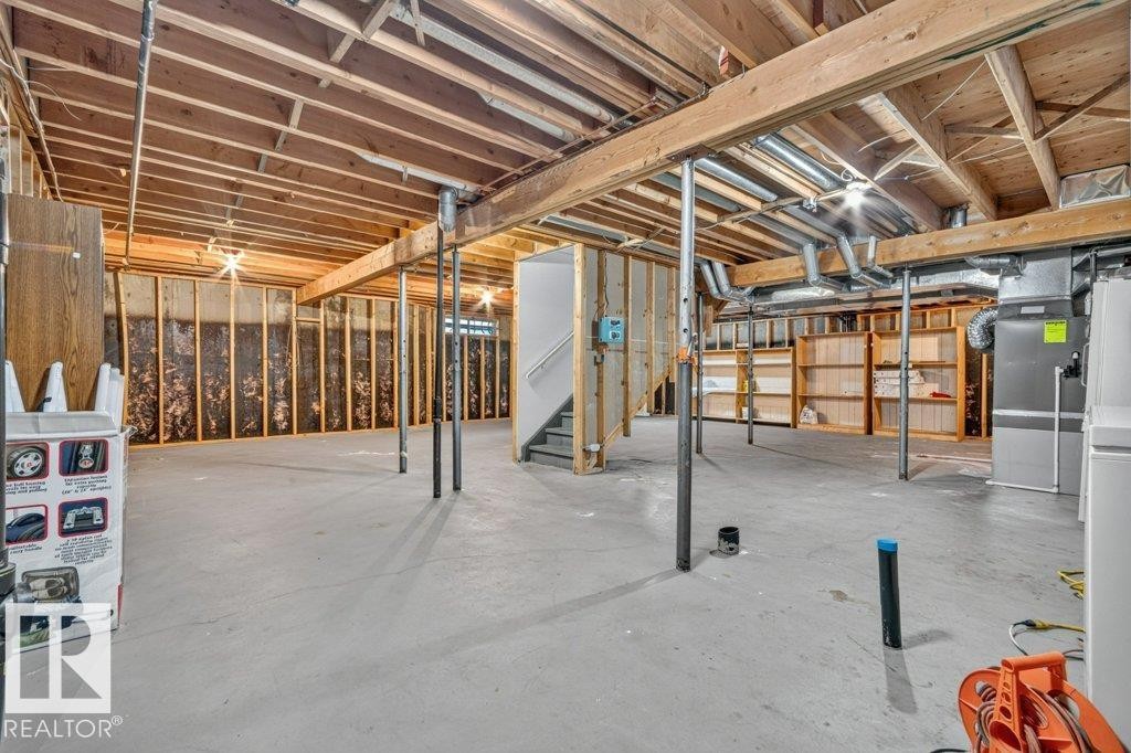 Expansive unfinished basement featuring a concrete floor, exposed wood ceiling joists, framed walls, a visible staircase, and mechanical systems - 16524 99 Street Nw, Edmonton, AB - Indoor Photo Showing Basement