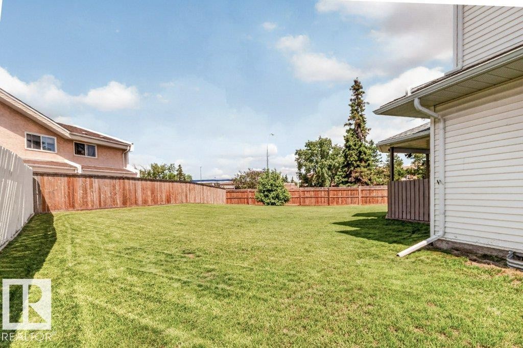 Expansive grassy backyard featuring a full wood privacy fence and a white vinyl privacy fence - 16524 99 Street Nw, Edmonton, AB - Outdoor