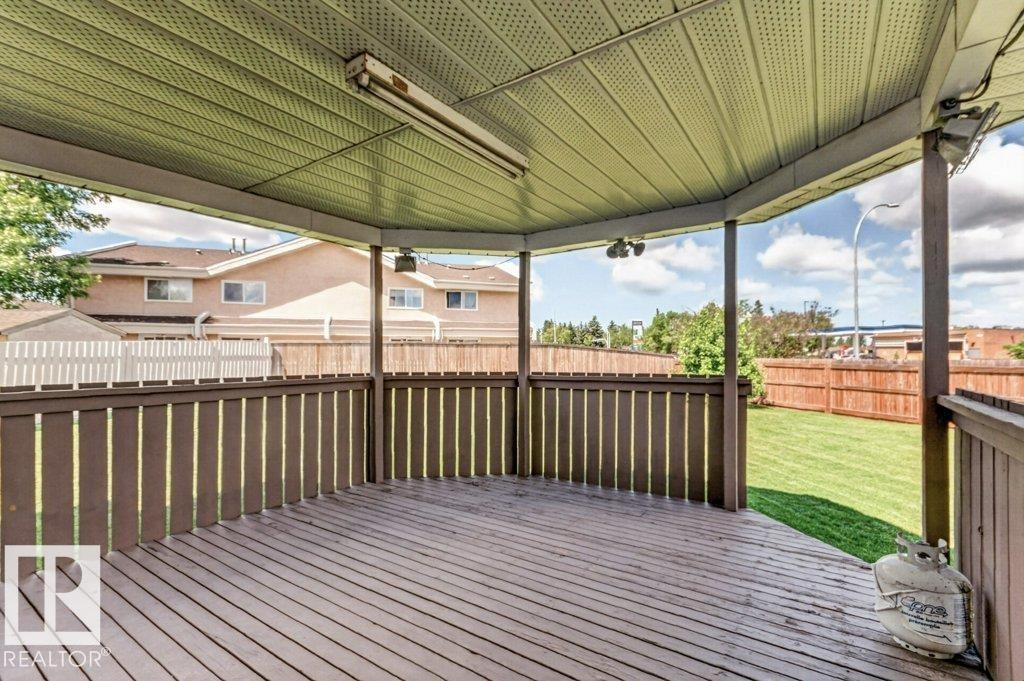 Covered outdoor deck with wood-finish flooring, surrounding dark wood-finish railing, and a slatted light-toned ceiling - 16524 99 Street Nw, Edmonton, AB - Outdoor With Deck Patio Veranda With Exterior