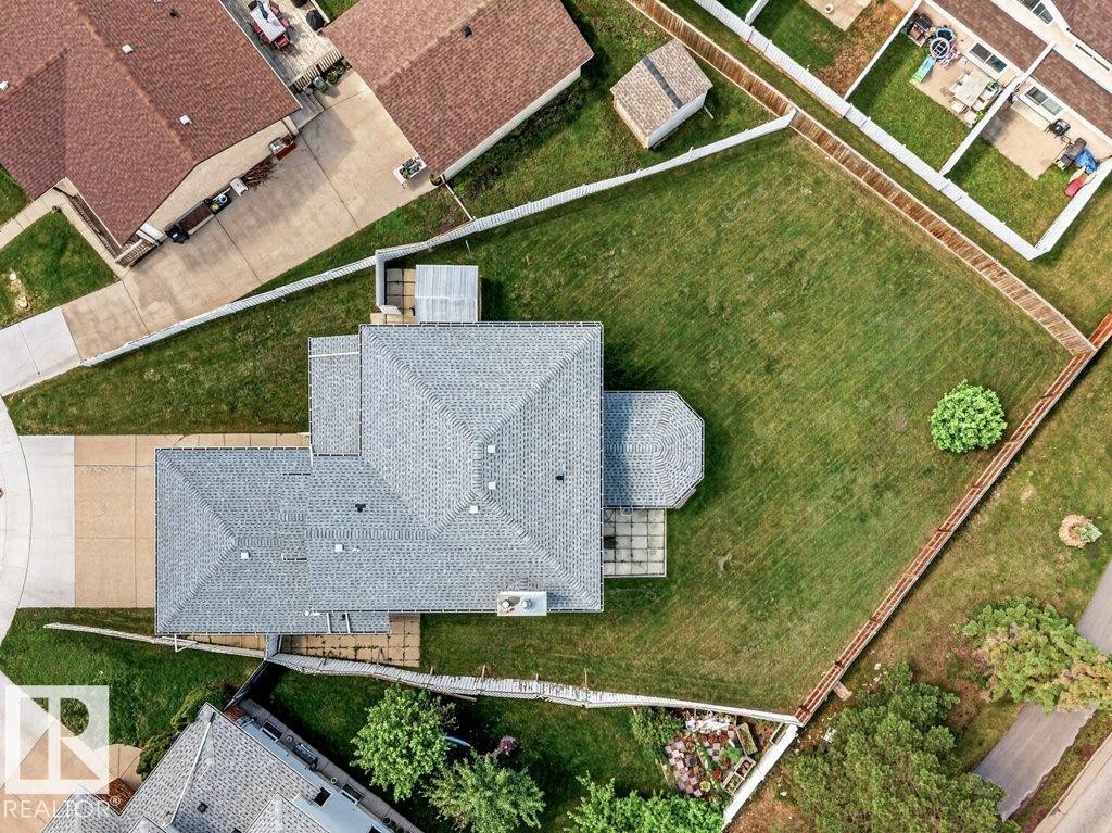 Expansive property featuring a gabled roofline, a large green lawn, a concrete driveway, a rear patio area, and a detached shed - 16524 99 Street Nw, Edmonton, AB - Outdoor