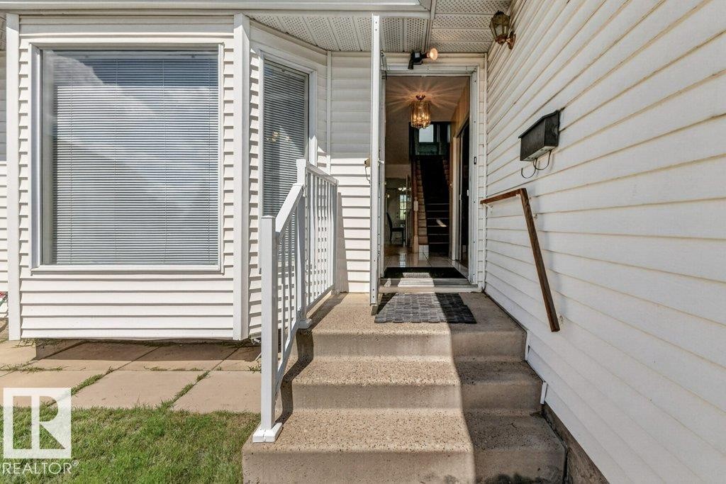 Front entryway featuring concrete steps, white railings, and a bay window - 16524 99 Street Nw, Edmonton, AB - Outdoor With Exterior