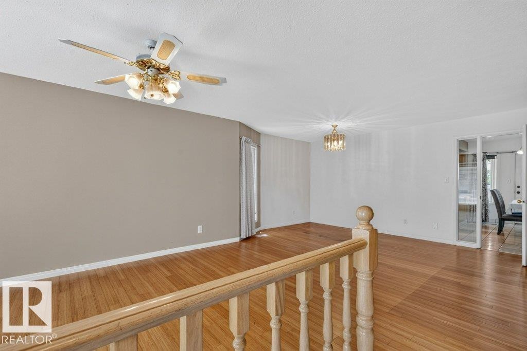 Open living area featuring wood-finish flooring and a neutral color palette - 16524 99 Street Nw, Edmonton, AB - Indoor Photo Showing Other Room