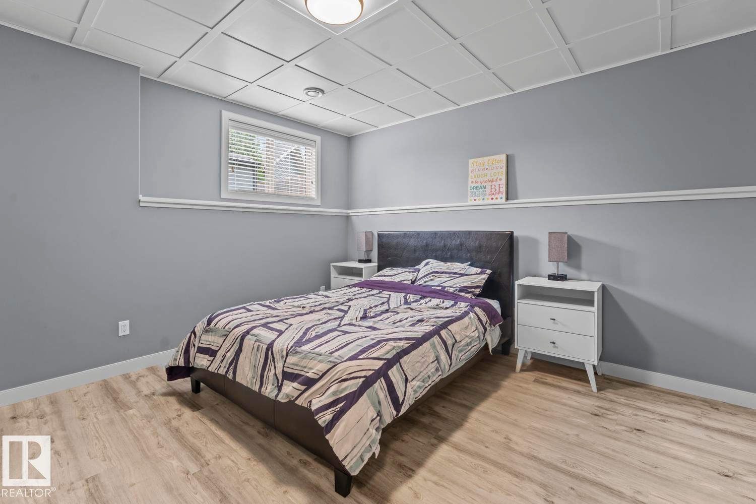 Bedroom featuring wood-finish flooring, a drop ceiling, window with blinds, and light gray painted walls with white trim - 35 Falcon Road, Cold Lake, AB