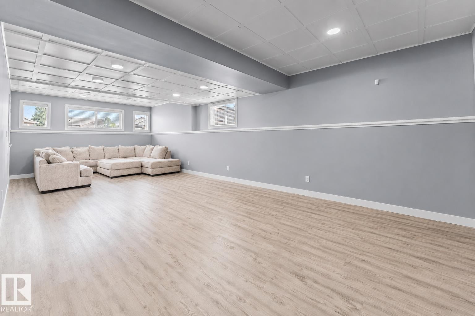 Spacious room featuring light wood-finish flooring, light gray walls with white trim, recessed lighting, and multiple windows - 35 Falcon Road, Cold Lake, AB