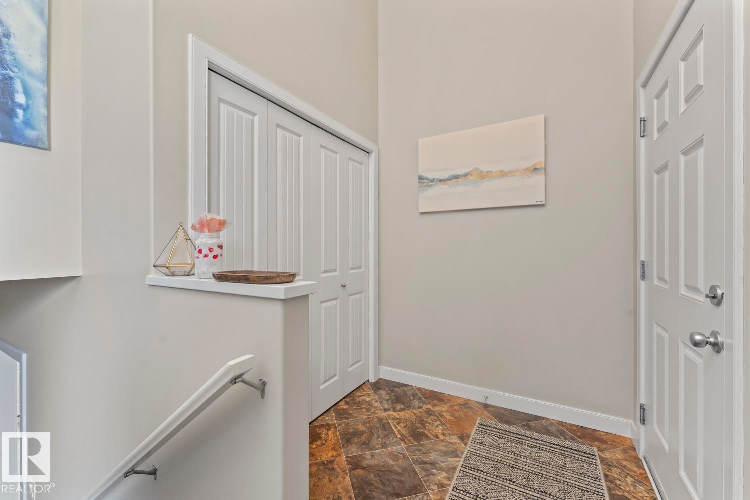 Entryway featuring durable slate-look tile flooring, a paneled entry door with brushed nickel hardware, and a bifold closet - 35 Falcon Road, Cold Lake, AB