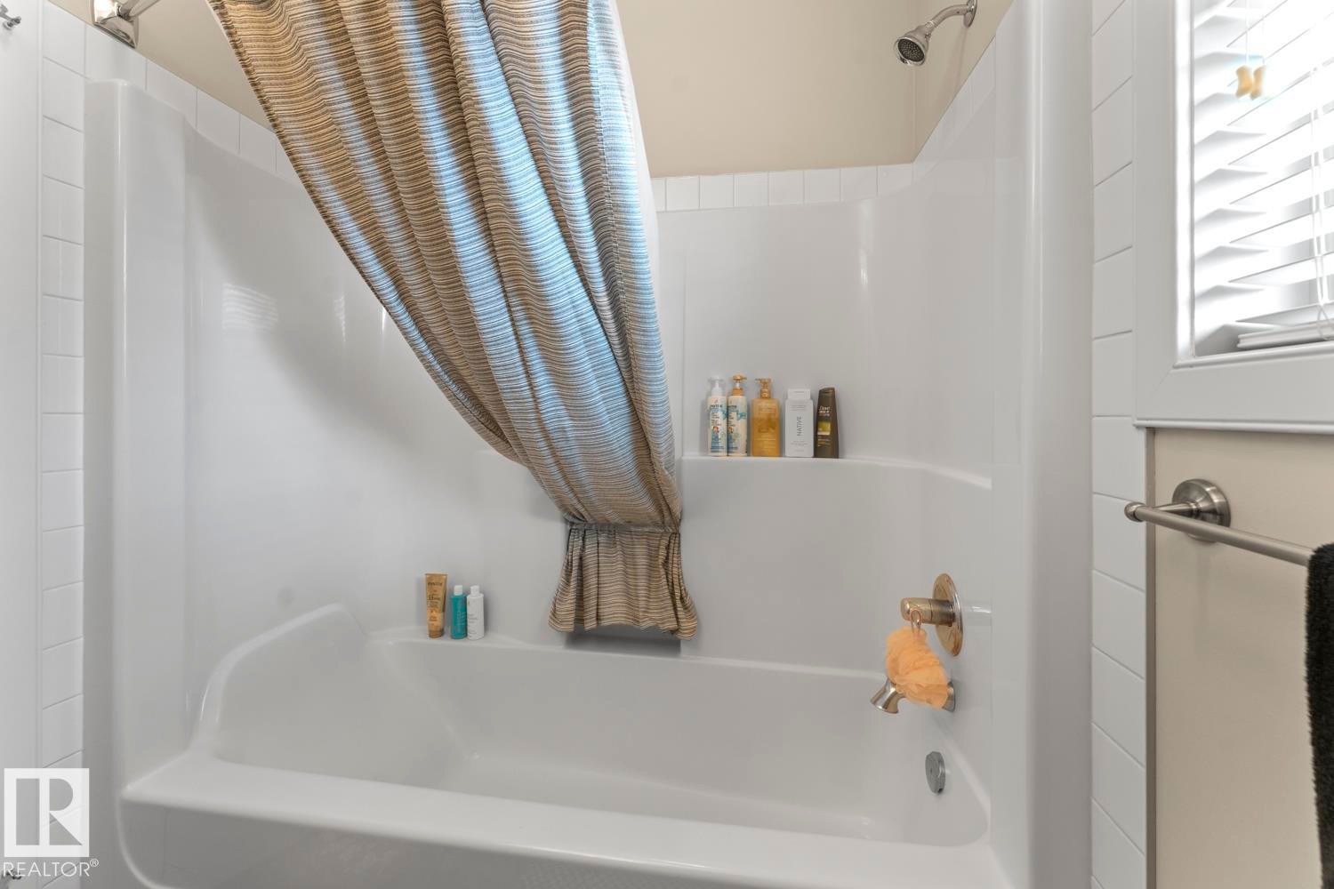 Bathroom featuring a white bathtub and shower combination with an integrated shelving unit - 35 Falcon Road, Cold Lake, AB