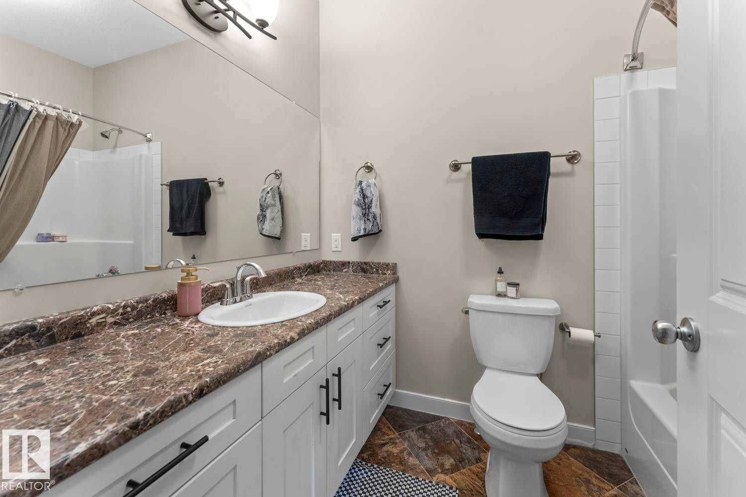 Full bathroom featuring a white vanity with dark hardware, a brown-toned countertop, and an undermount sink with a chrome faucet - 35 Falcon Road, Cold Lake, AB