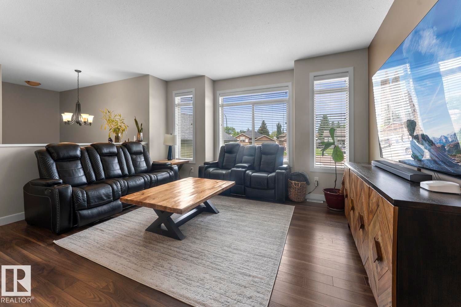 Spacious living area featuring wood-finish flooring, a light-toned area rug, and multiple windows with blinds - 35 Falcon Road, Cold Lake, AB