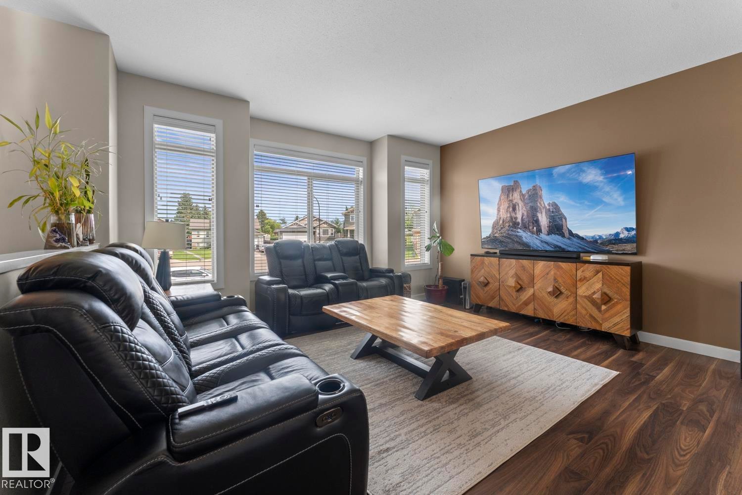 Spacious living area featuring large windows with horizontal blinds, wood-finish flooring, and a neutral wall palette - 35 Falcon Road, Cold Lake, AB
