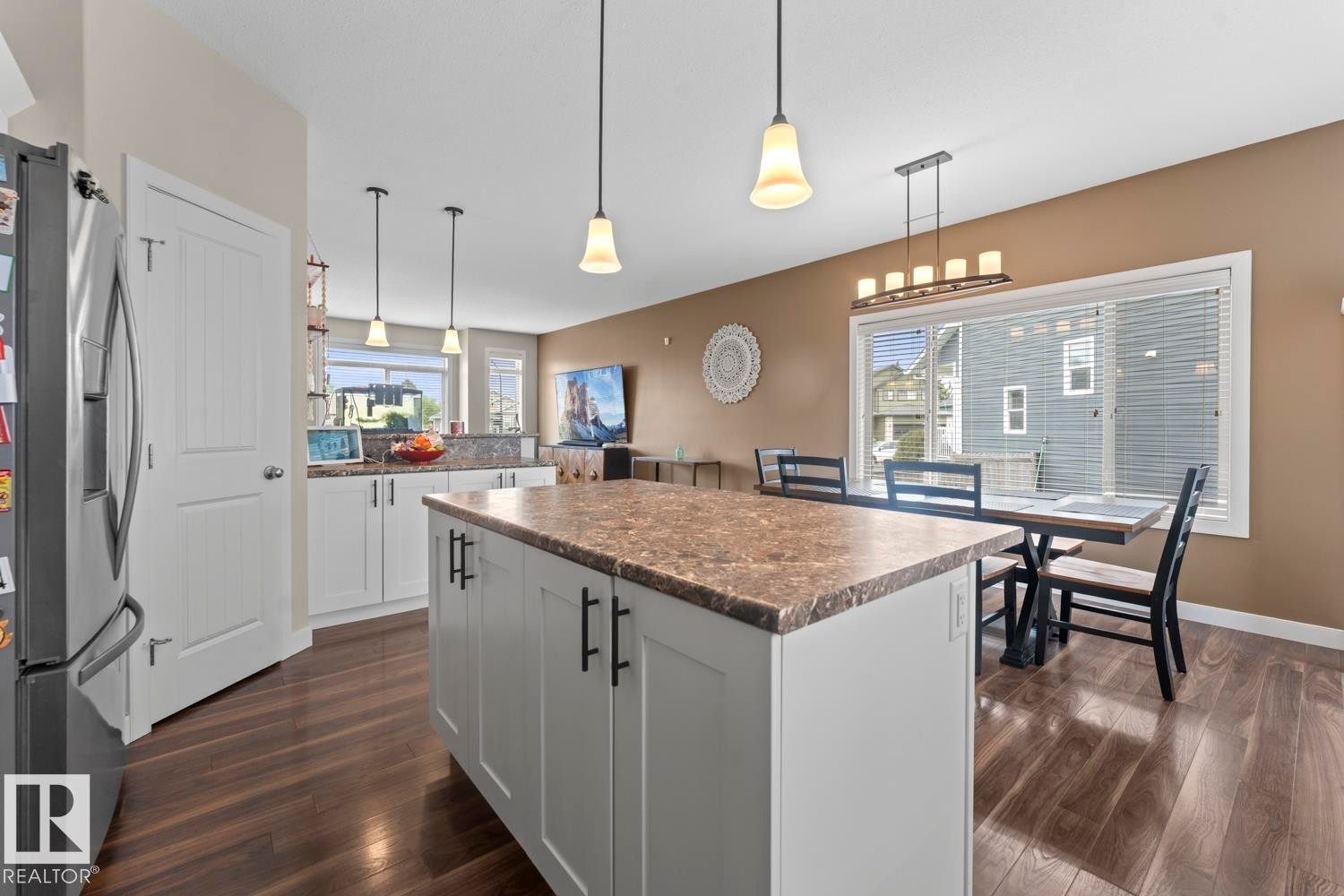 Kitchen featuring a central island with a stone-finish countertop, white cabinetry, dark hardware, and wood-finish flooring - 35 Falcon Road, Cold Lake, AB