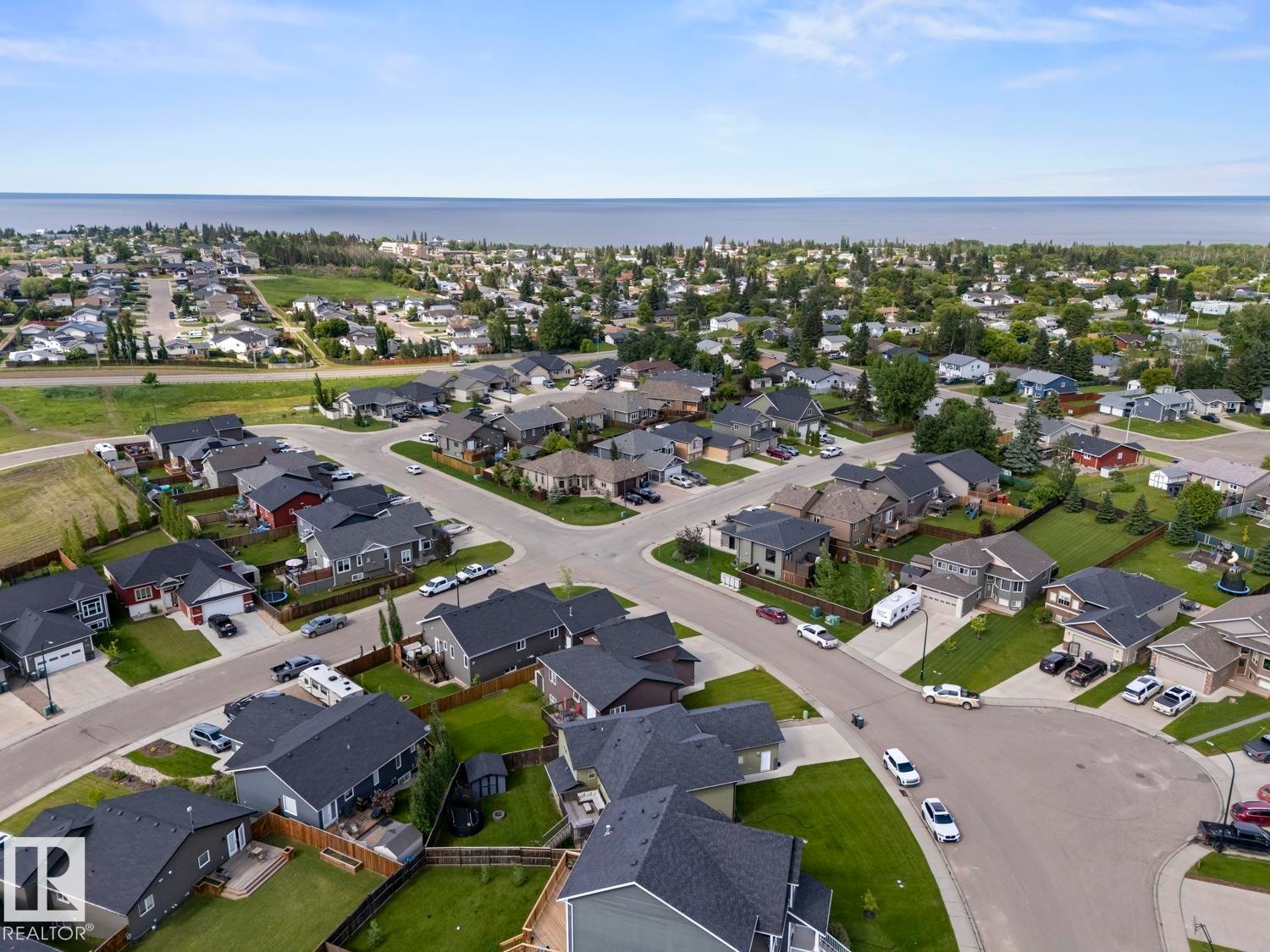 Aerial perspective of a residential neighborhood featuring single-family homes with dark-shingle roofs and green landscaping - 35 Falcon Road, Cold Lake, AB