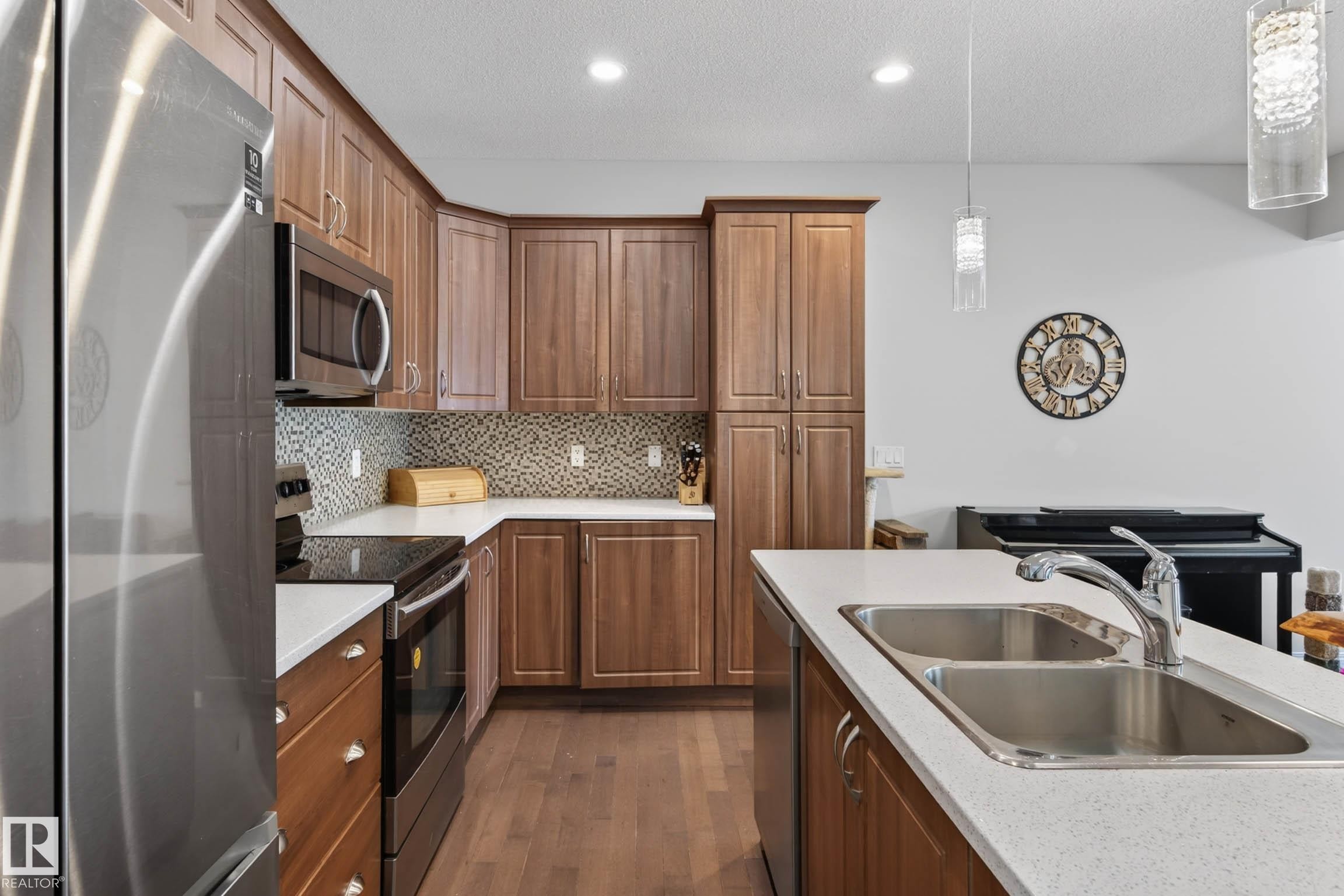 Kitchen with wood-finish cabinetry, stainless steel appliances, and a mosaic tile backsplash - 2007 72 Street, Edmonton, AB - Indoor Photo Showing Kitchen With Double Sink With Upgraded Kitchen