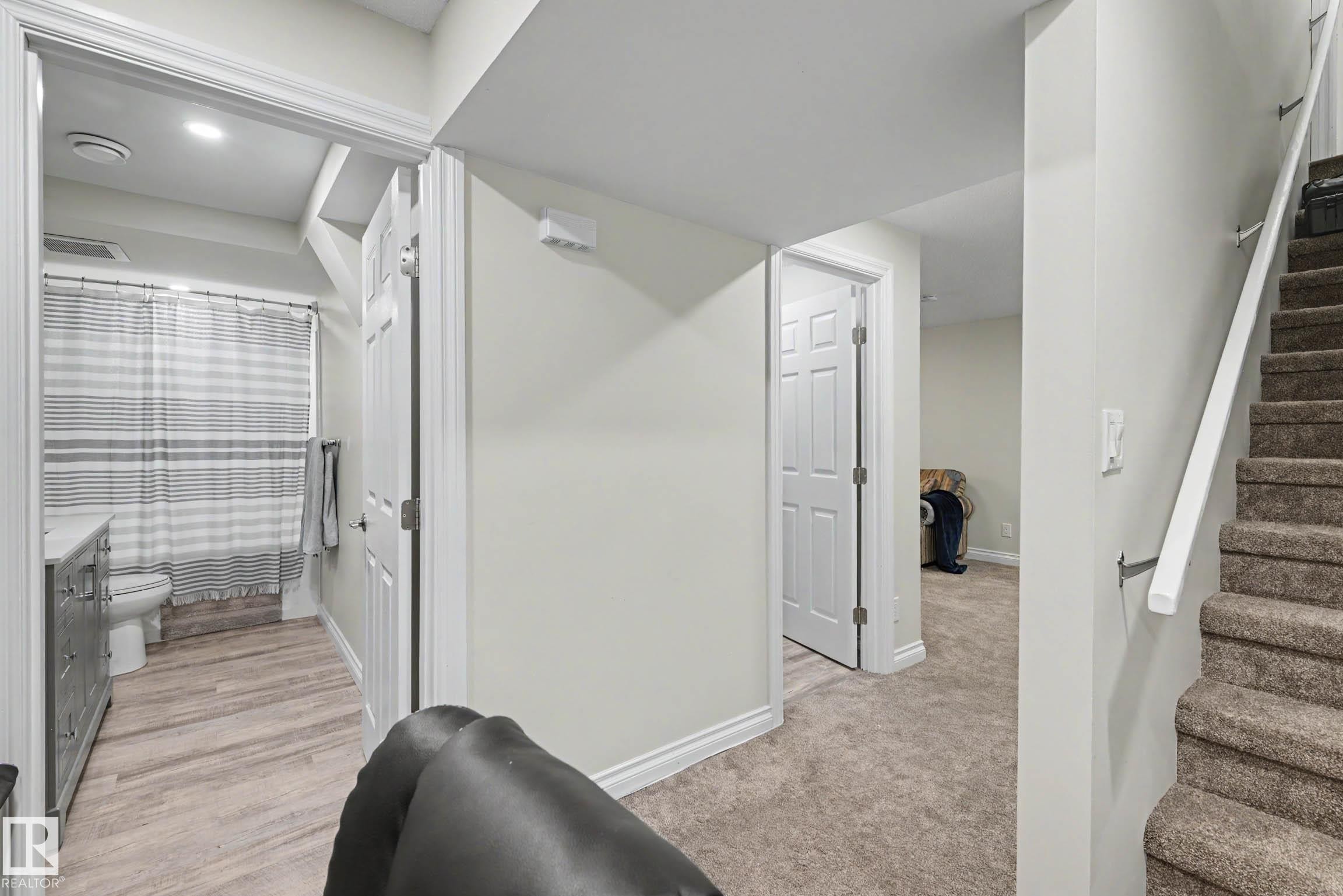 Carpeted stairway with white railing, leading to a hallway with wood-finish flooring and a white paneled door - 2007 72 Street, Edmonton, AB - Indoor Photo Showing Other Room