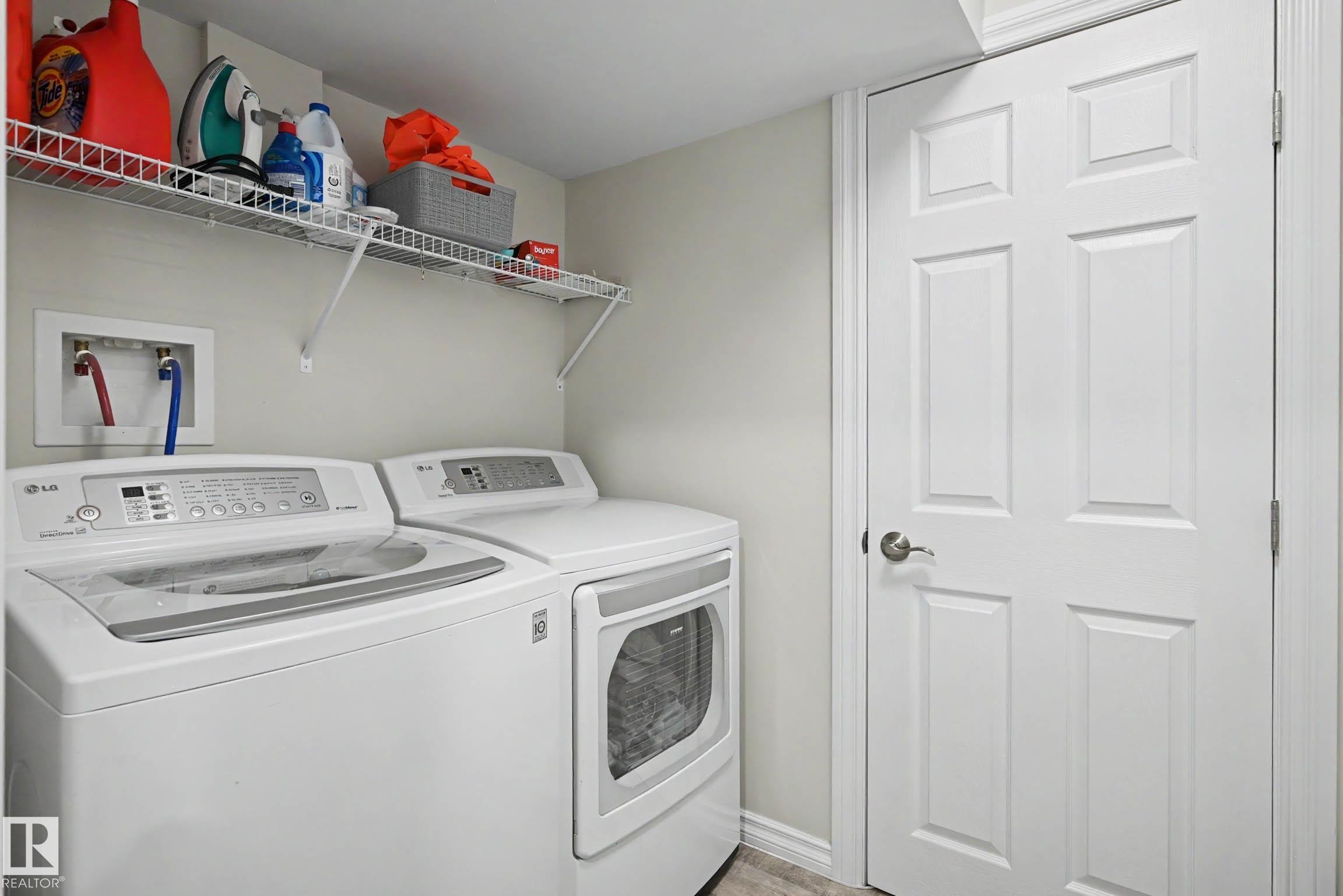 Dedicated laundry area featuring a washer and dryer, an overhead wire shelving unit, and a six-panel interior door - 2007 72 Street, Edmonton, AB - Indoor Photo Showing Laundry Room