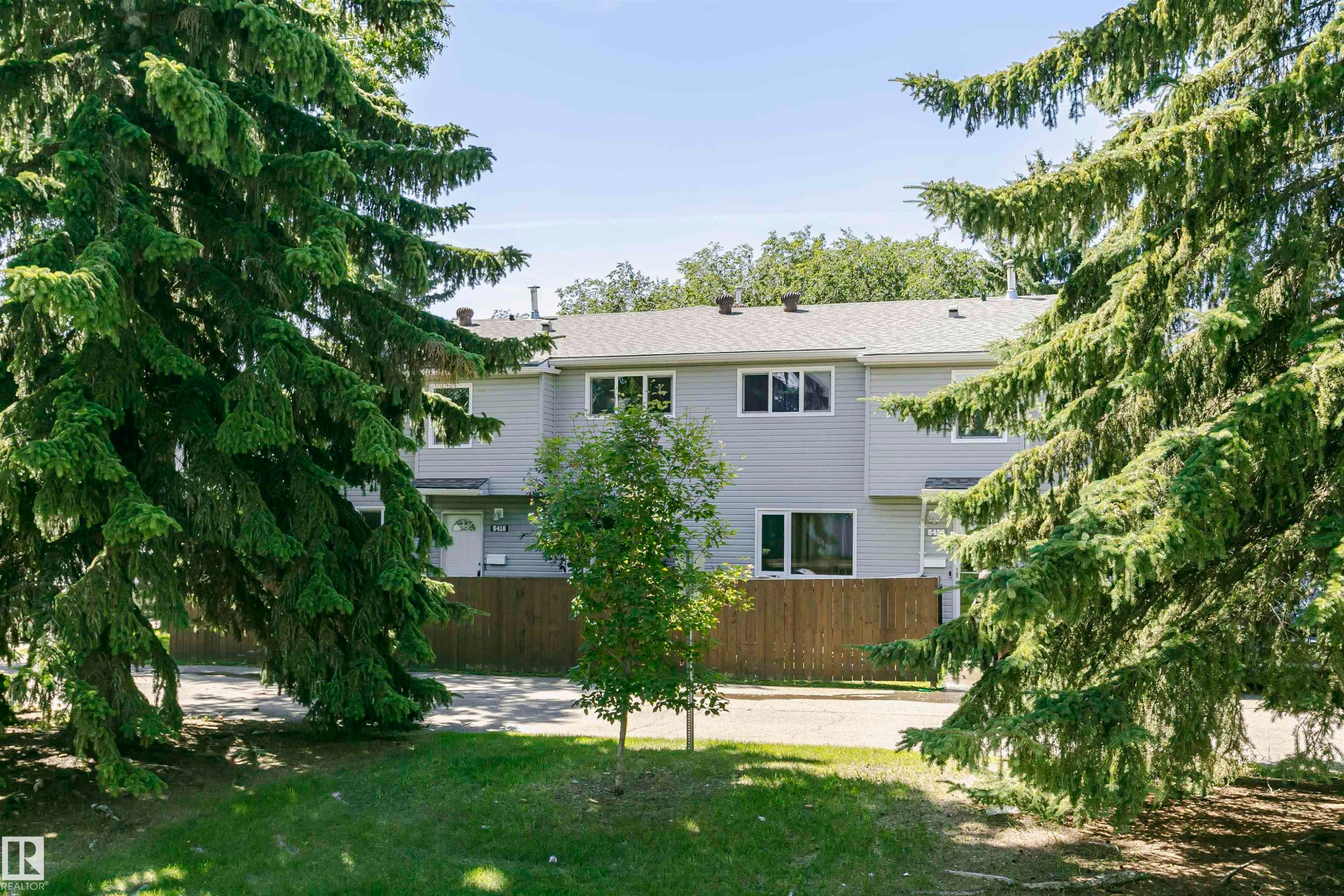 Contemporary townhouse exterior featuring light grey siding and a dark roof - 5418 144B Avenue, Edmonton, AB