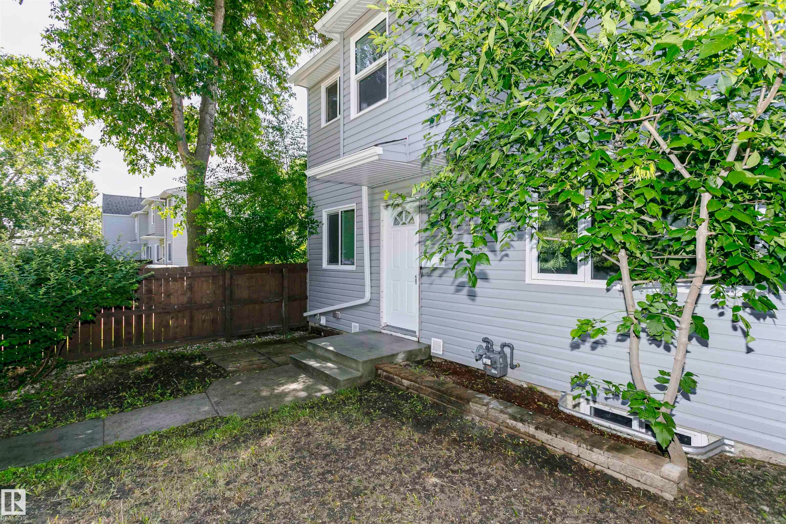 Gray siding exterior with white trim windows and a white entry door - 5418 144B Avenue, Edmonton, AB